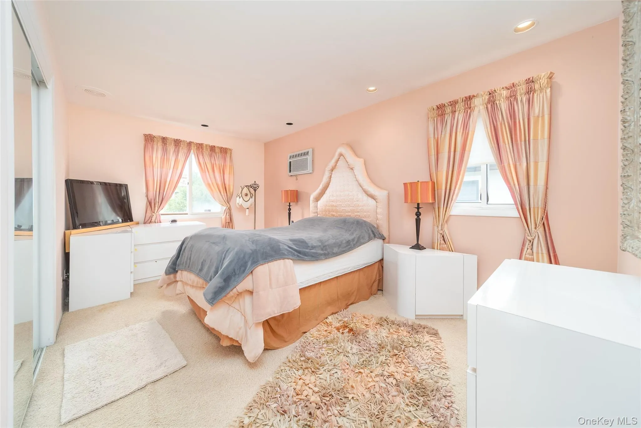 Bedroom featuring light carpet, a wall mounted air conditioner, and recessed lighting Bedroom featuring light carpet, a wall mounted air conditioner, and recessed lighting
