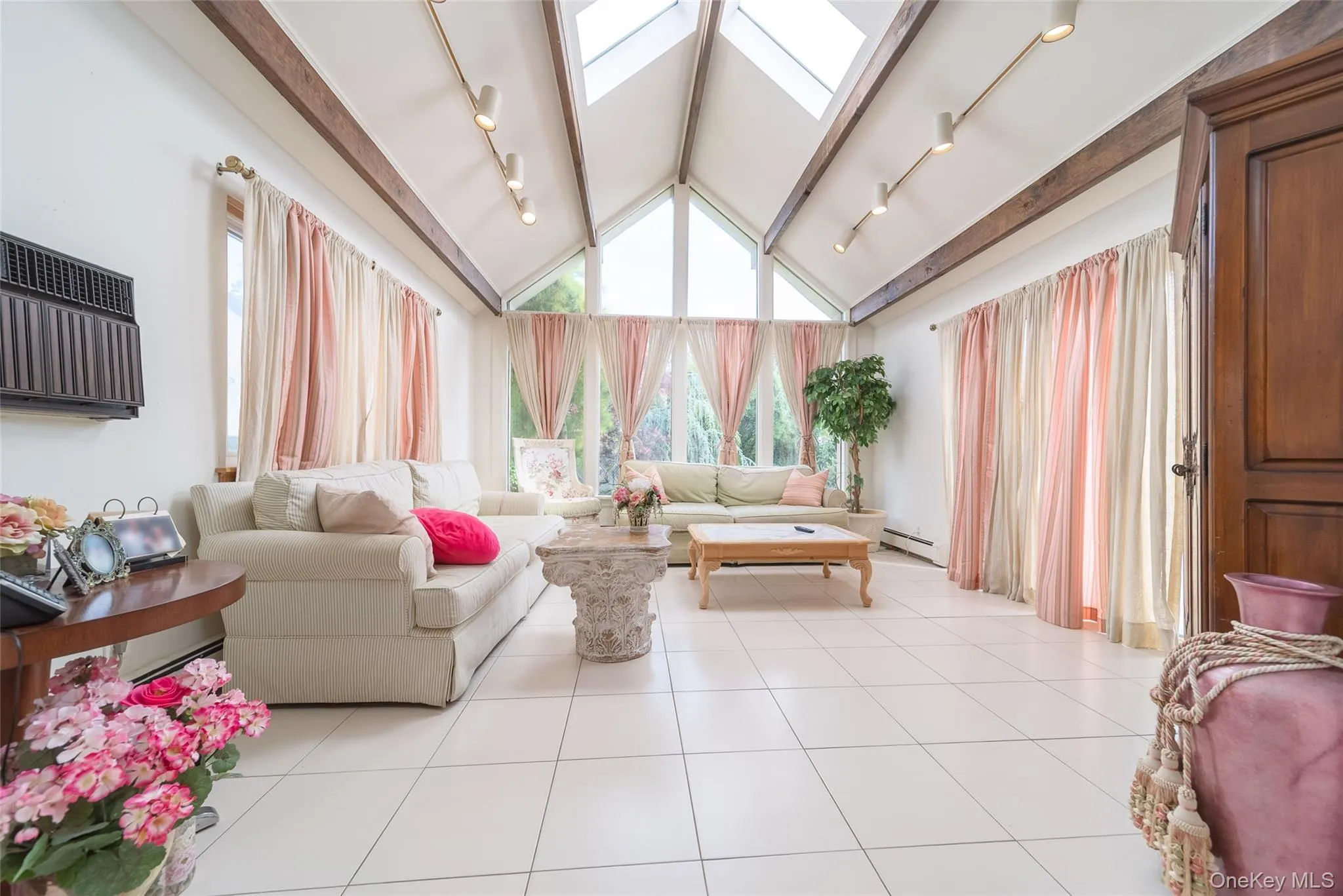 Living room with a wall mounted air conditioner, a baseboard radiator, and rail lighting Living room with a wall mounted air conditioner, a baseboard radiator, and rail lighting