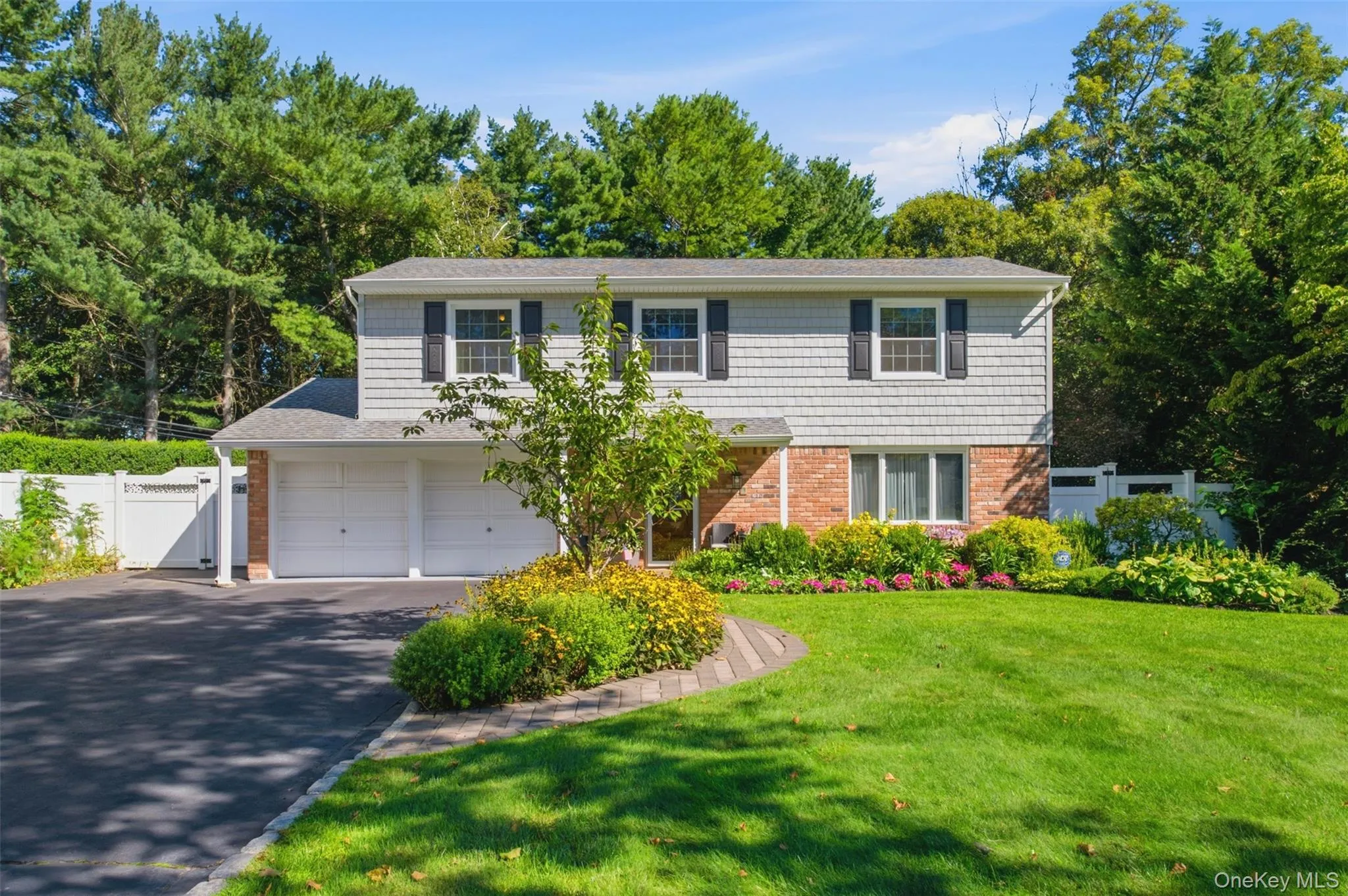 Two-story residence featuring a shingle and brick exterior, two-car garage, and a paved driveway Two-story residence featuring a shingle and brick exterior, two-car garage, and a paved driveway