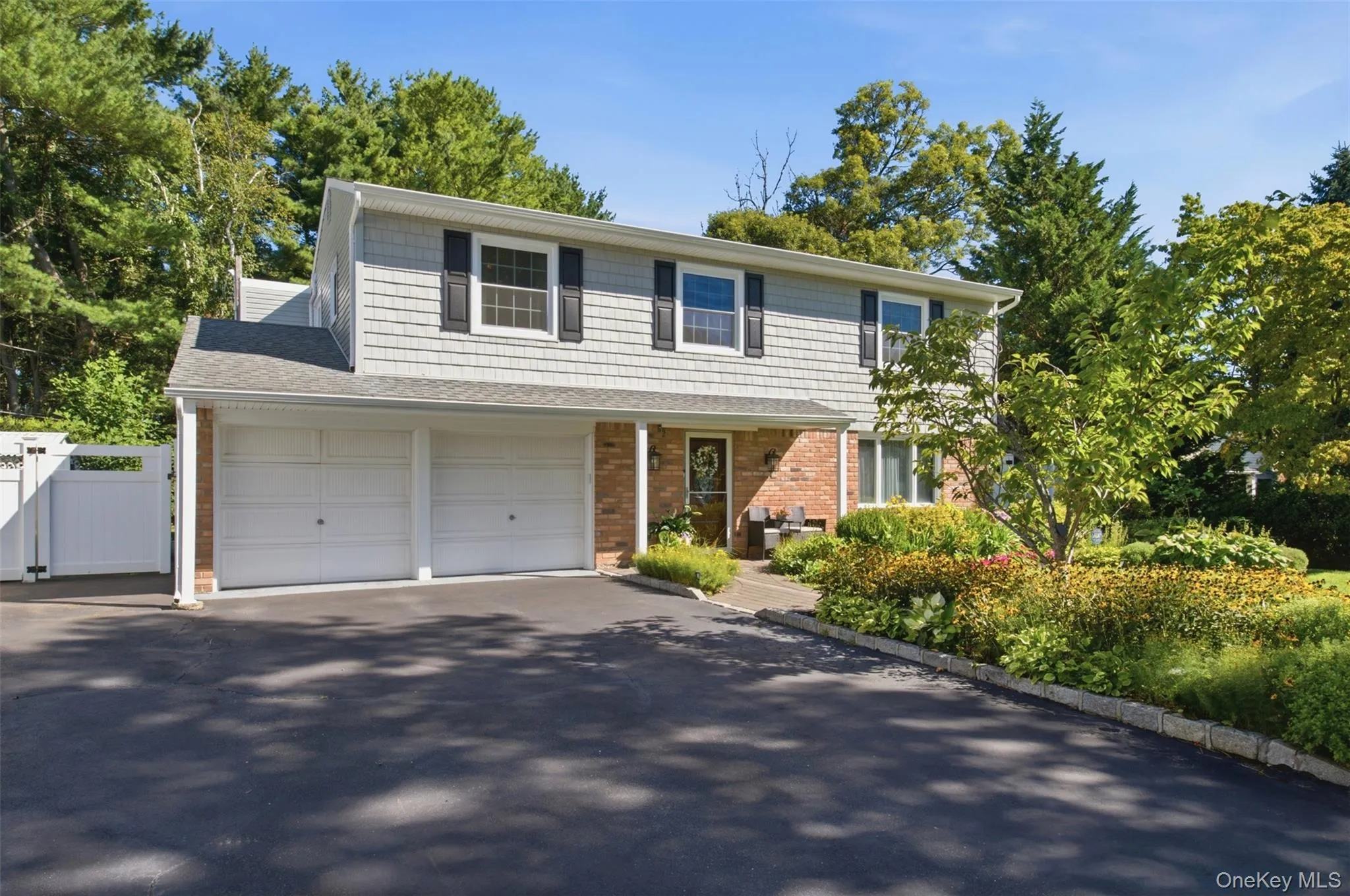 Two-story residence featuring light gray siding and brick facade Two-story residence featuring light gray siding and brick facade