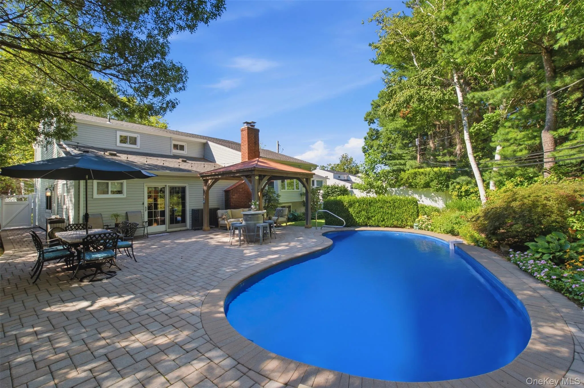 Freeform swimming pool with a paver surround, expansive patio, and an outdoor gazebo Freeform swimming pool with a paver surround, expansive patio, and an outdoor gazebo