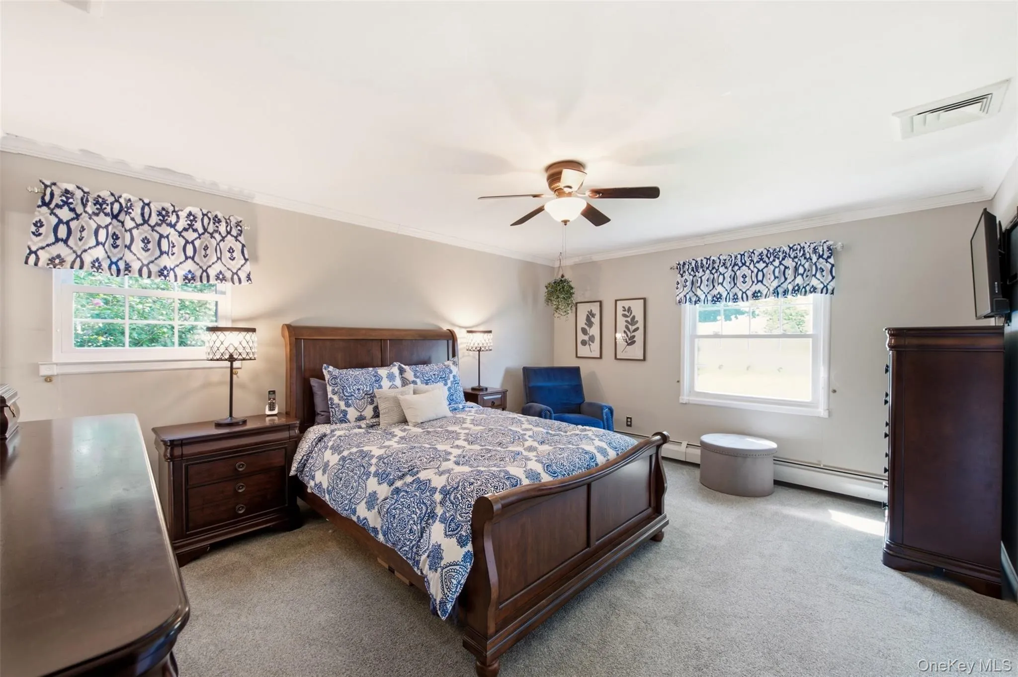Carpeted room with a ceiling fan light fixture, two windows, and crown molding Carpeted room with a ceiling fan light fixture, two windows, and crown molding