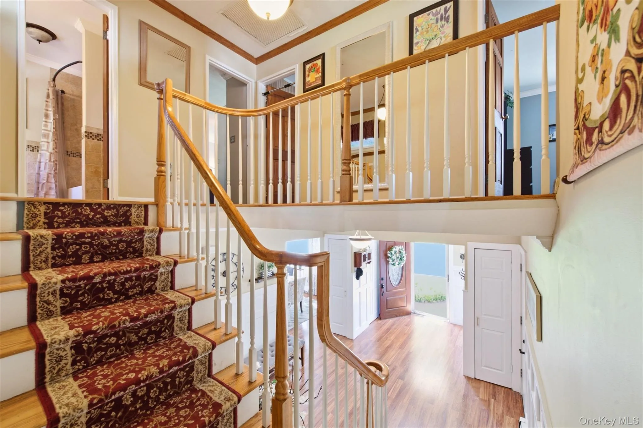 Multi-level interior featuring a wood-finish staircase with decorative runner, a wood handrail with white balusters, and wood-finish flooring on the lower level Multi-level interior featuring a wood-finish staircase with decorative runner, a wood handrail with white balusters, and wood-finish flooring on the lower level