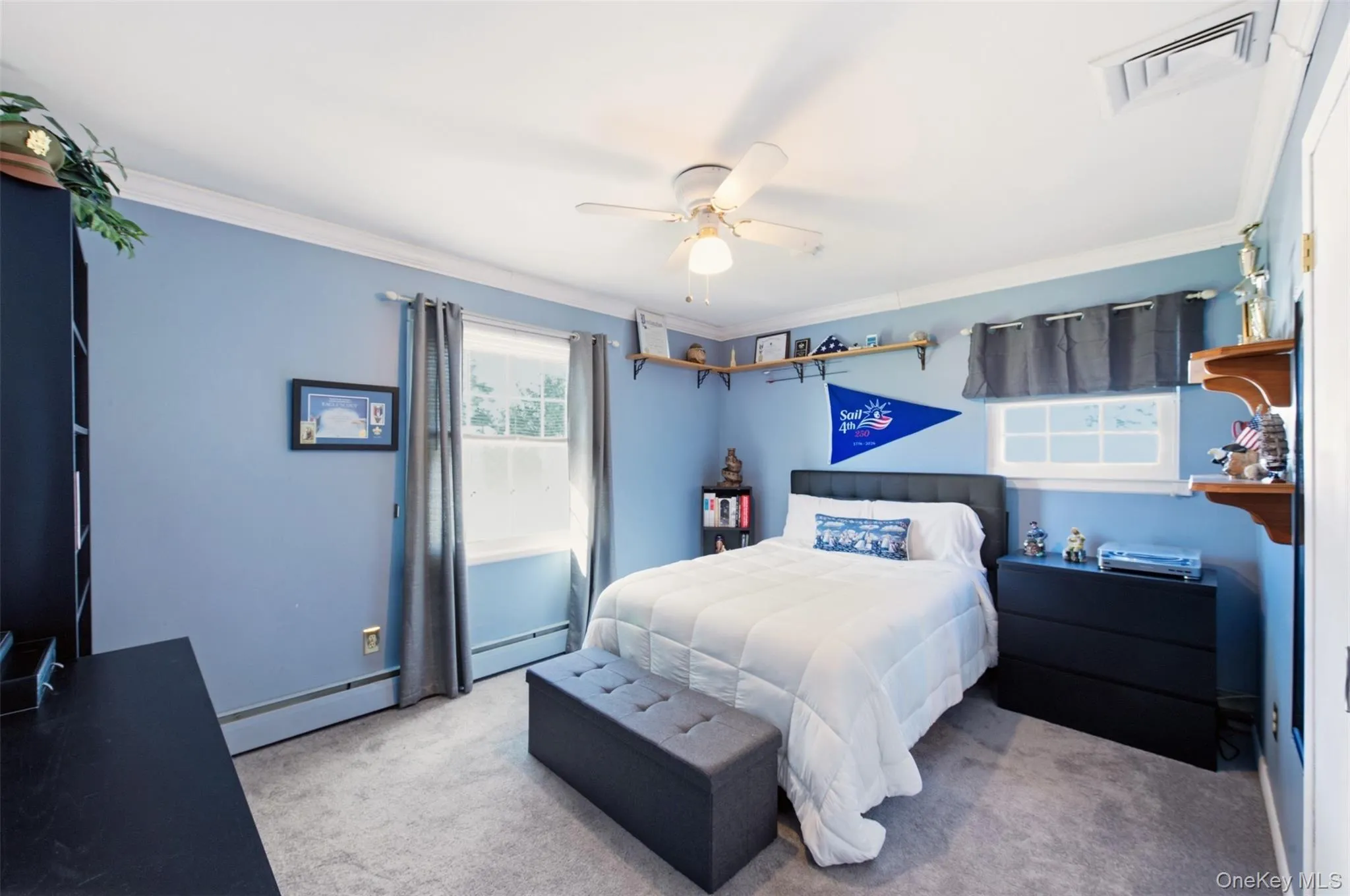 Room featuring crown molding, two windows, wall-mounted shelving, and a ceiling fan Room featuring crown molding, two windows, wall-mounted shelving, and a ceiling fan