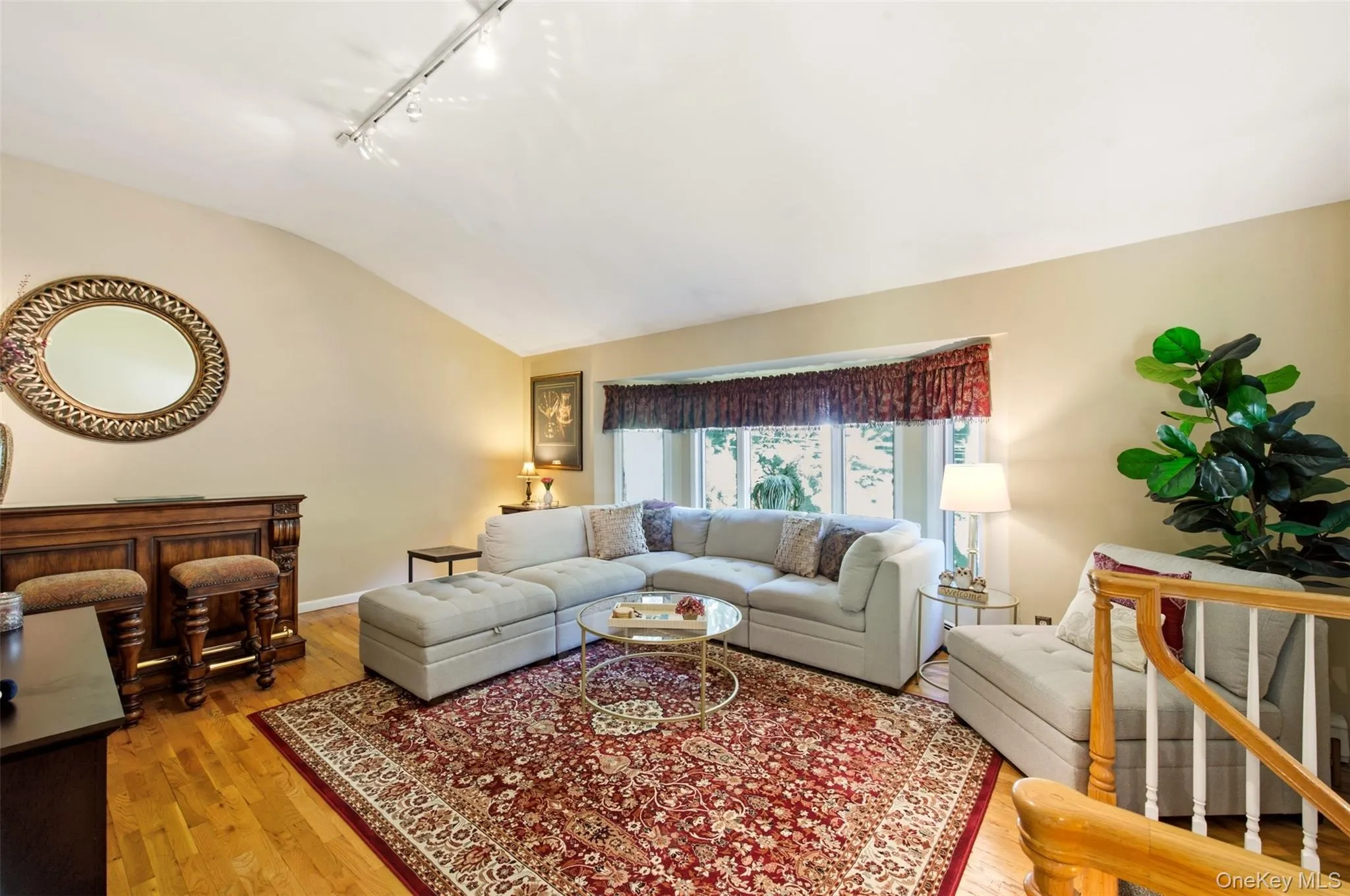 Vaulted ceiling with track lighting, hardwood flooring, and a bay window Vaulted ceiling with track lighting, hardwood flooring, and a bay window
