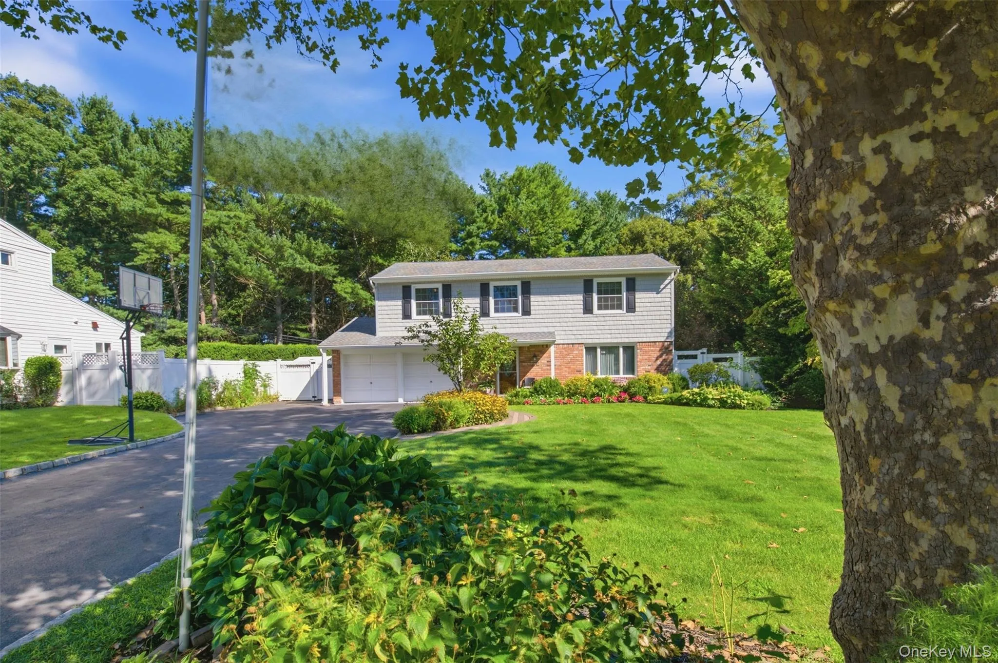 Split-level residence featuring a brick and siding facade, attached two-car garage, expansive front lawn, and mature landscaping Split-level residence featuring a brick and siding facade, attached two-car garage, expansive front lawn, and mature landscaping