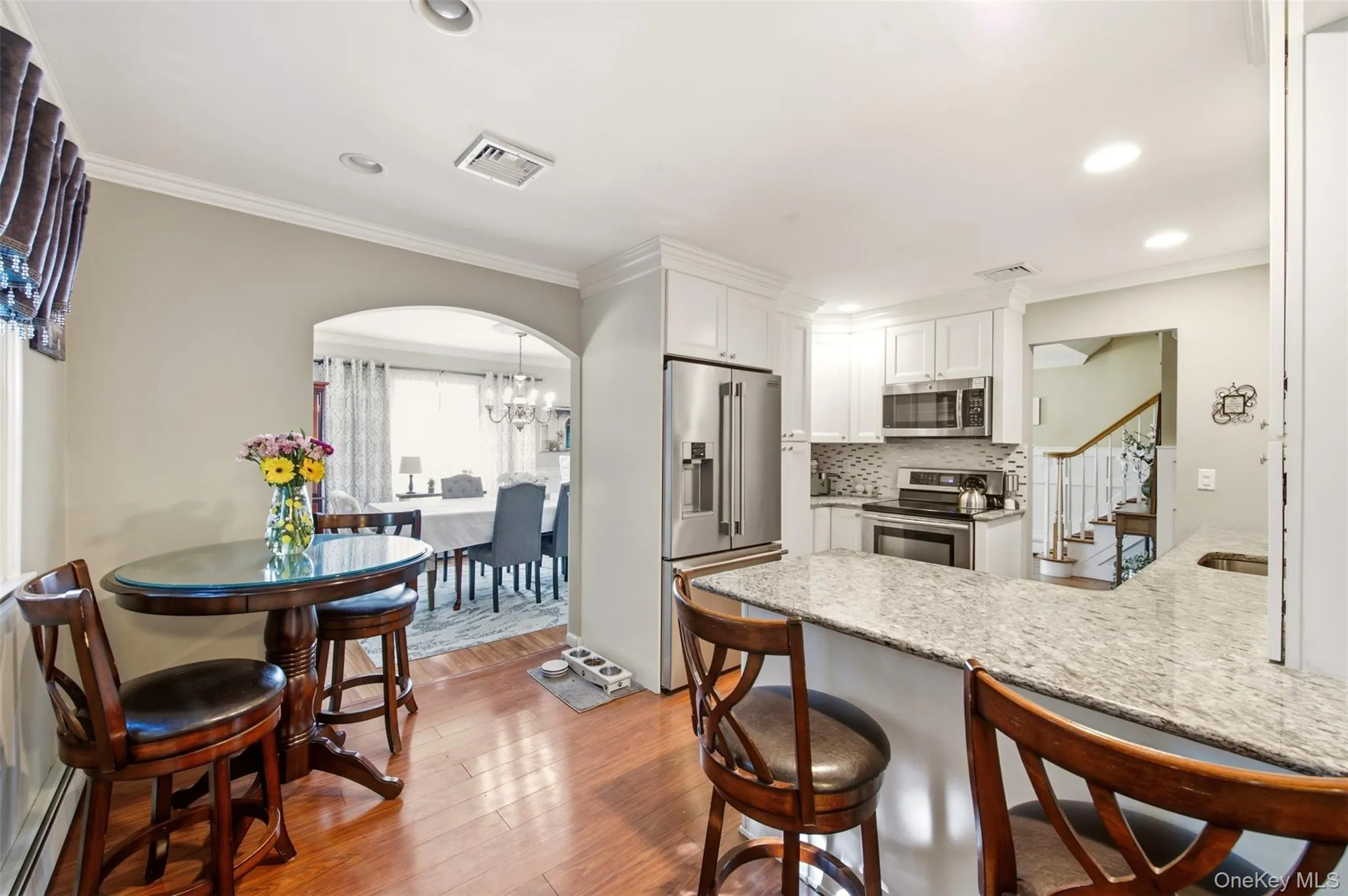 Kitchen featuring white cabinetry, stainless steel appliances, a light-toned countertop, and wood-finish flooring Kitchen featuring white cabinetry, stainless steel appliances, a light-toned countertop, and wood-finish flooring