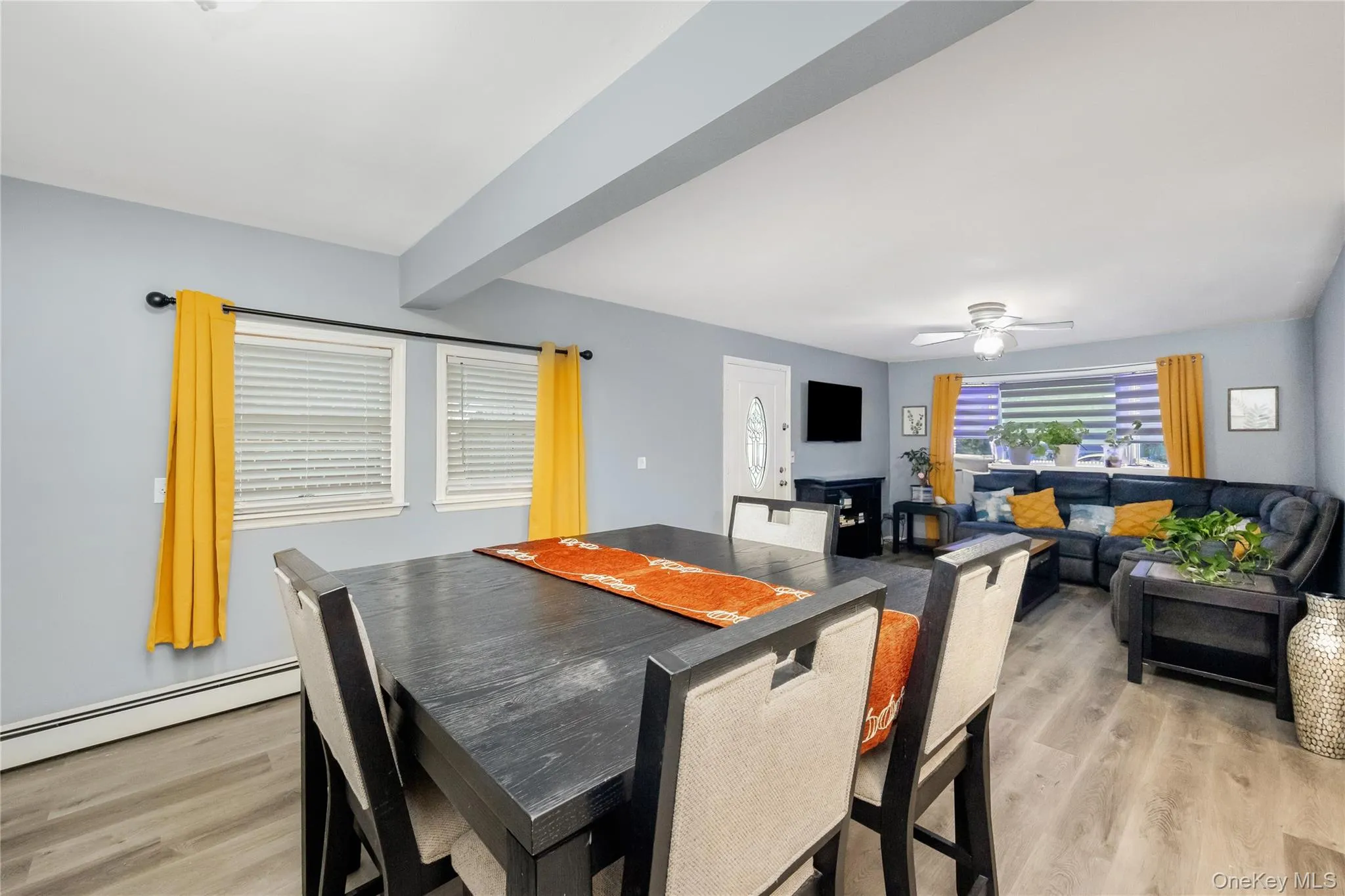Dining room featuring light wood-style floors, a baseboard heating unit, a ceiling fan, and beamed ceiling Dining room featuring light wood-style floors, a baseboard heating unit, a ceiling fan, and beamed ceiling