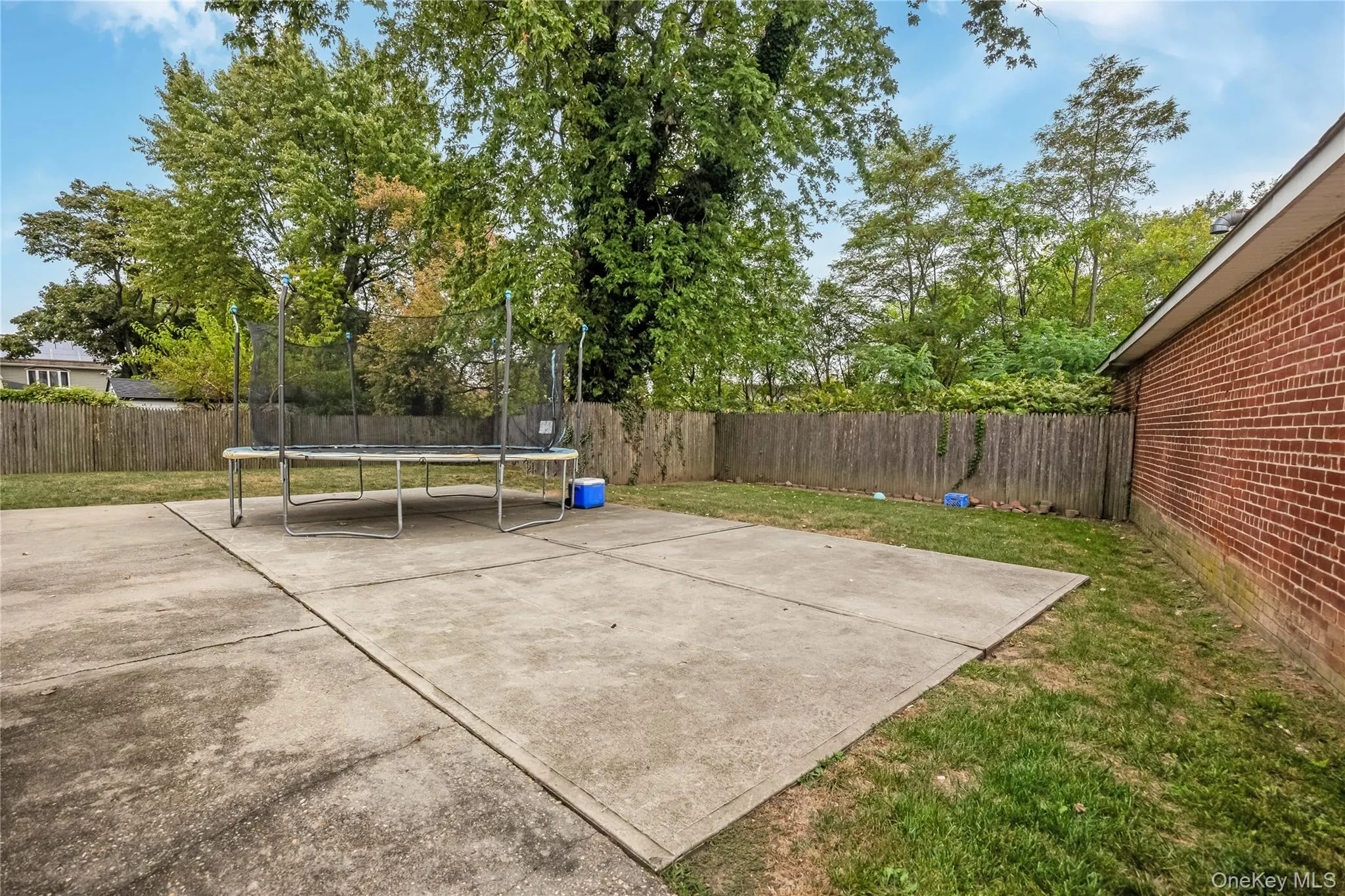 Fenced backyard with a trampoline and a patio area Fenced backyard with a trampoline and a patio area