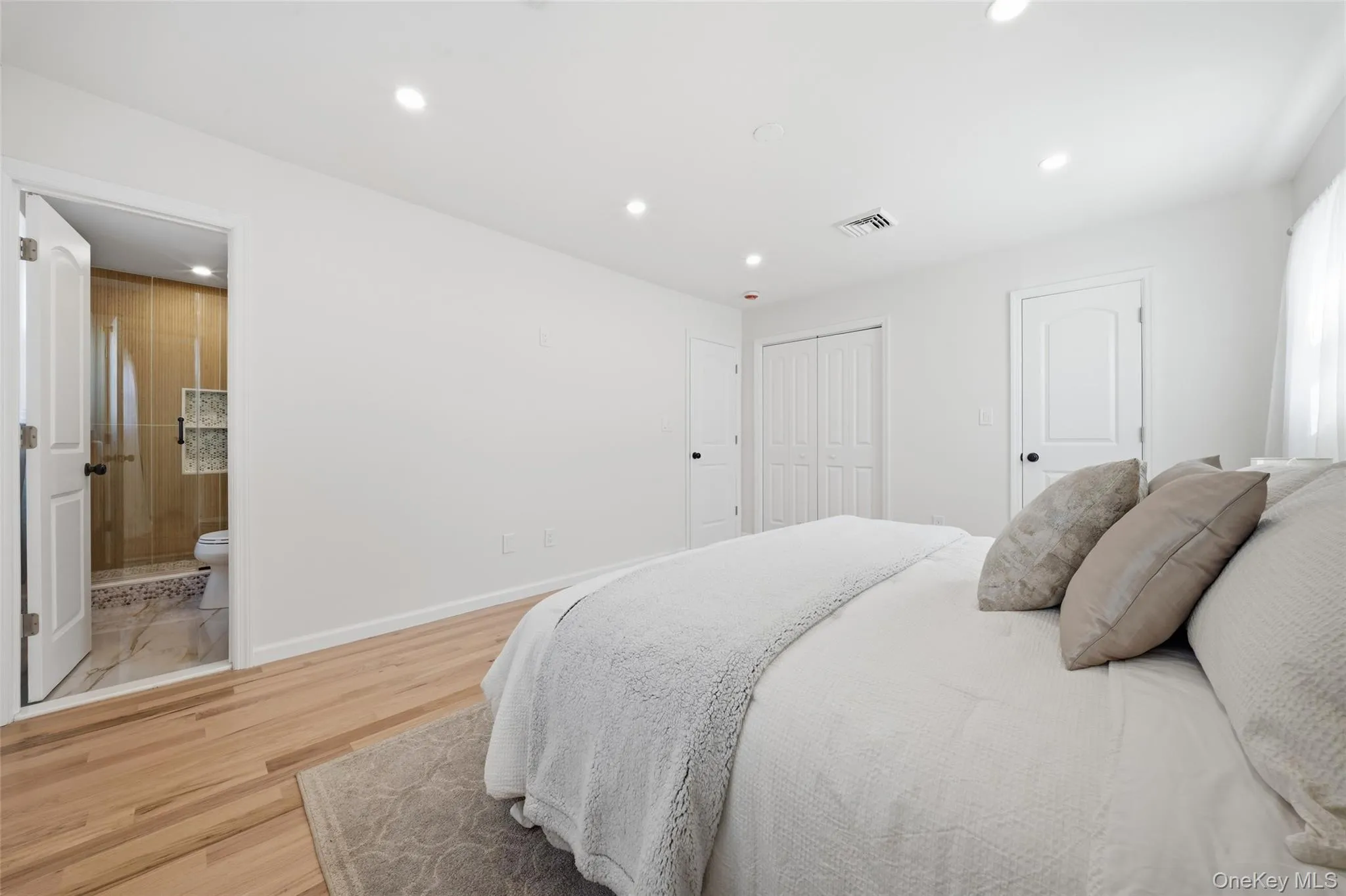 Premier Bedrom,Hardwood flooring, recessed lighting, white interior doors, bifold closet doors, and a bathroom with a glass-enclosed shower Premier Bedrom,Hardwood flooring, recessed lighting, white interior doors, bifold closet doors, and a bathroom with a glass-enclosed shower