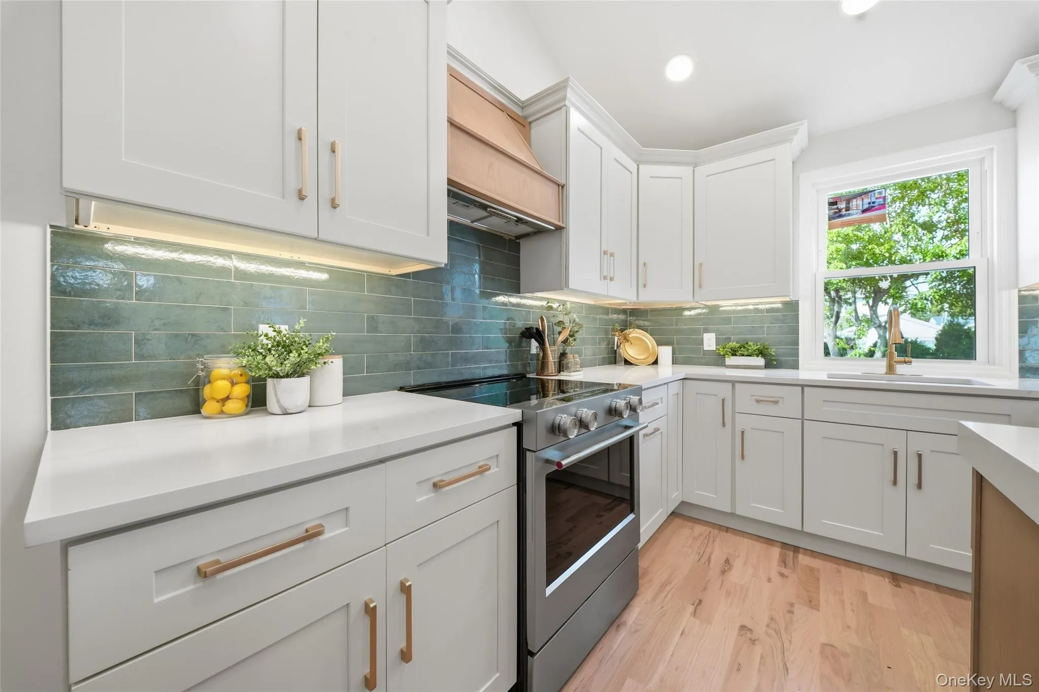 White shaker cabinetry, light-tone wood finish flooring, subway tile backsplash, white countertops, and a stainless steel range White shaker cabinetry, light-tone wood finish flooring, subway tile backsplash, white countertops, and a stainless steel range