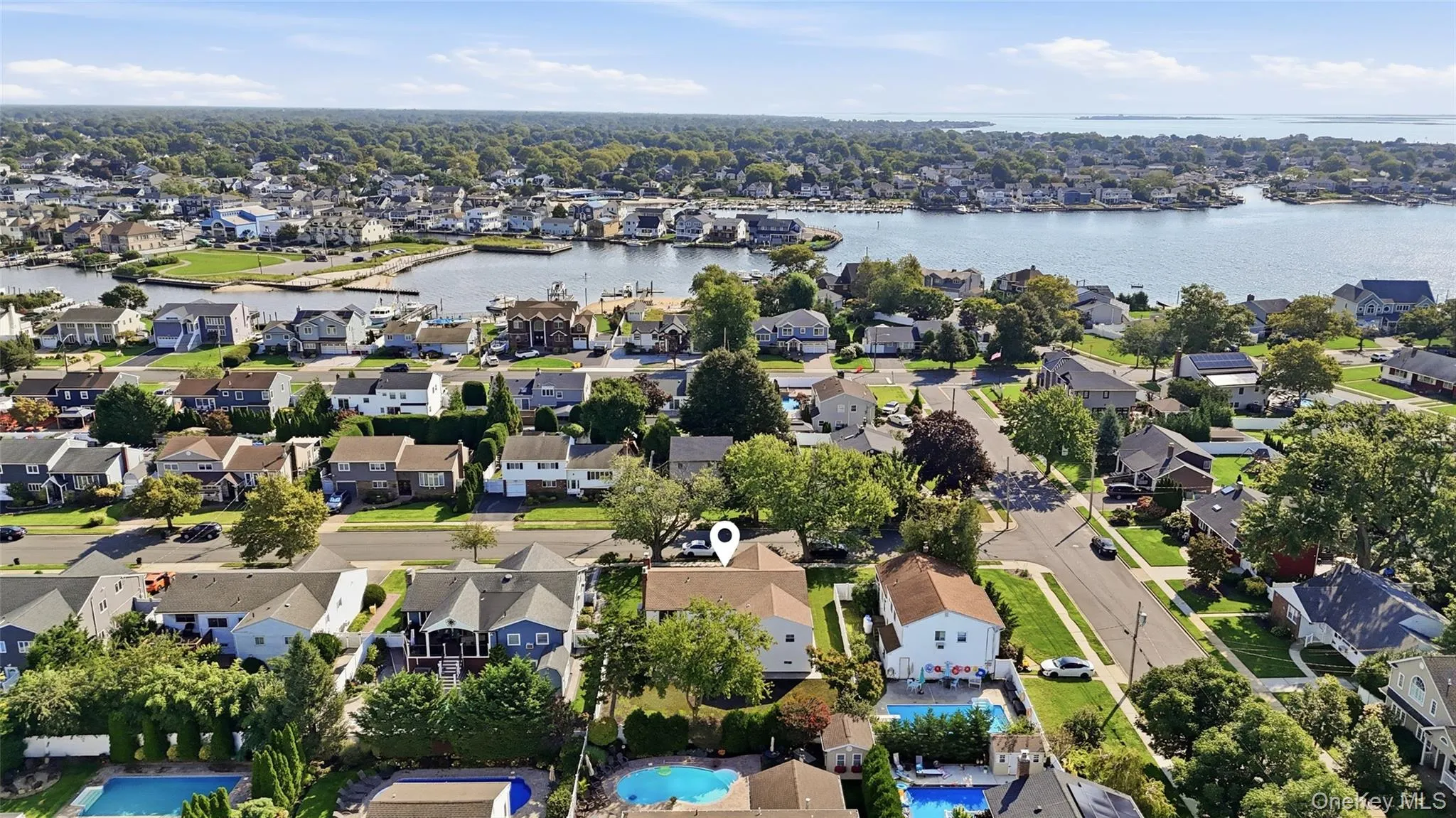 Aerial property overview featuring residential structures, surrounding greenery, and water frontage Aerial property overview featuring residential structures, surrounding greenery, and water frontage
