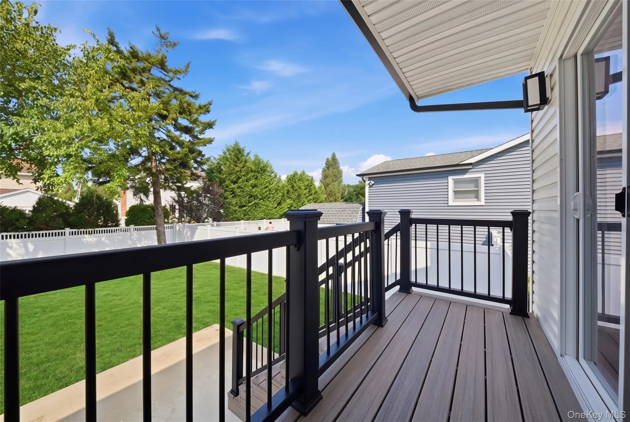 Outdoor deck with composite wood-finish flooring, black railing, and sliding glass door access Outdoor deck with composite wood-finish flooring, black railing, and sliding glass door access