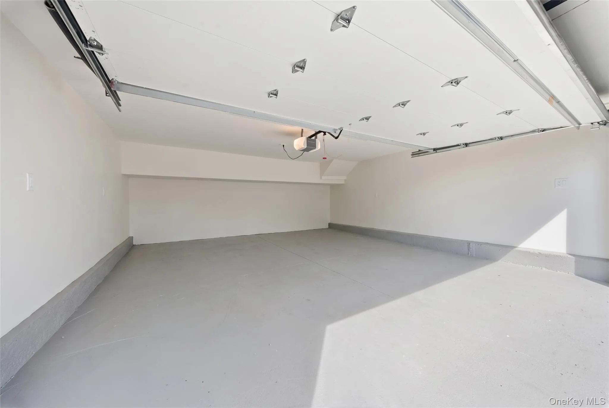Coated concrete flooring, painted white walls, and an automatic garage door opener Coated concrete flooring, painted white walls, and an automatic garage door opener