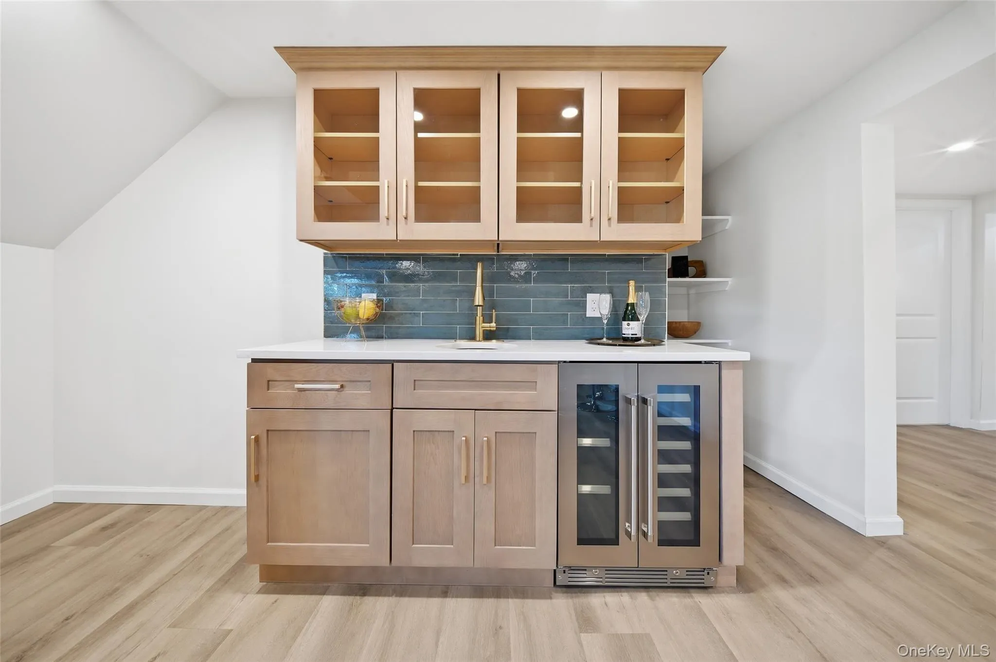 Wet bar featuring light wood-finish cabinetry, a white countertop, subway tile backsplash, and a built-in beverage refrigerator Wet bar featuring light wood-finish cabinetry, a white countertop, subway tile backsplash, and a built-in beverage refrigerator