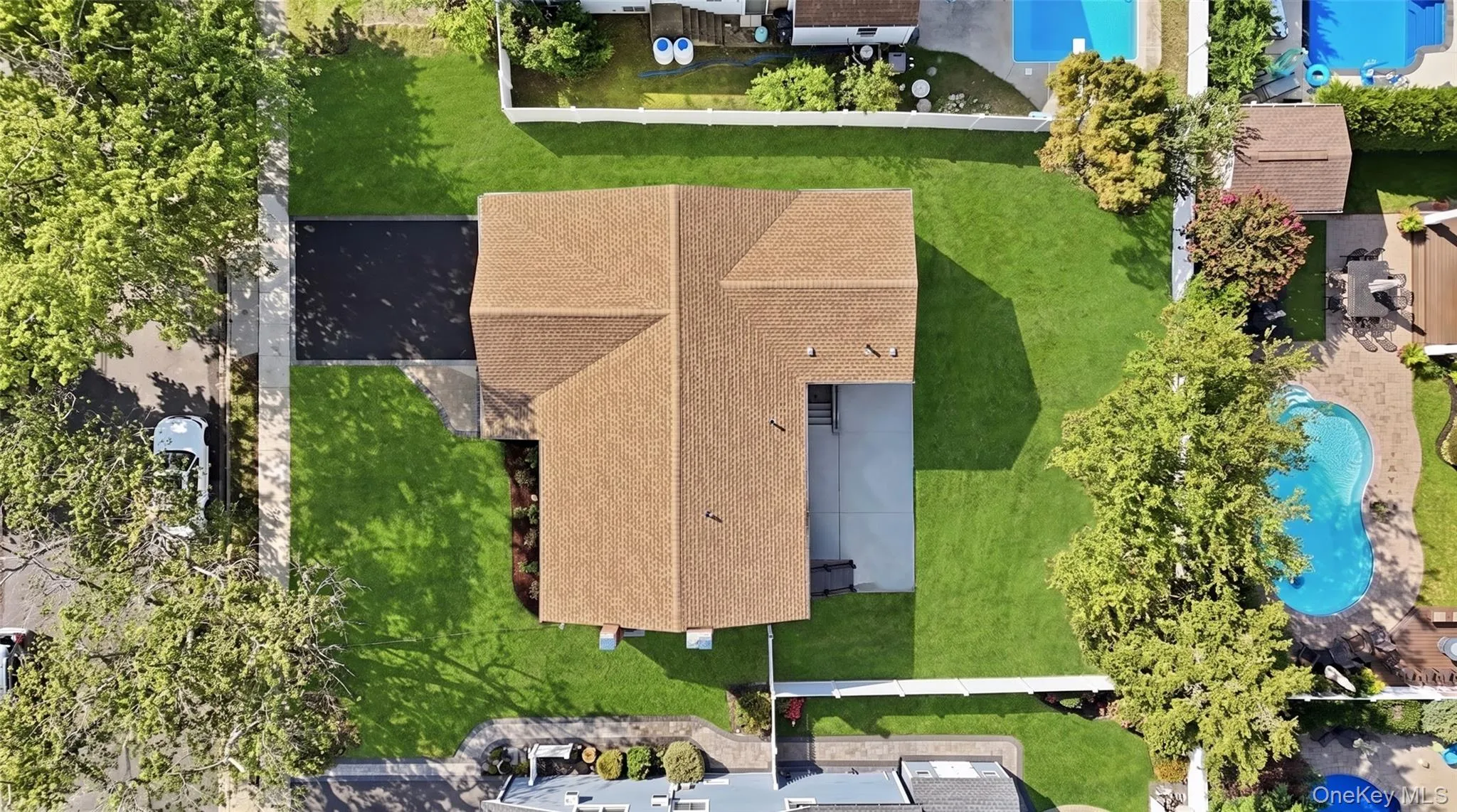 Extensive green lawn, asphalt driveway, mature trees, and a concrete patio Extensive green lawn, asphalt driveway, mature trees, and a concrete patio