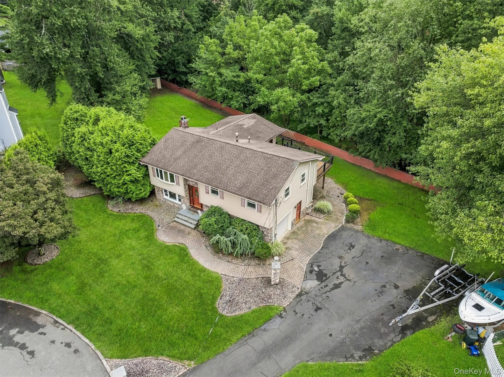 Split-level residence featuring a multi-tone exterior, a stone-accented entryway, a dark shingle roof, and long driveway Split-level residence featuring a multi-tone exterior, a stone-accented entryway, a dark shingle roof, and long driveway