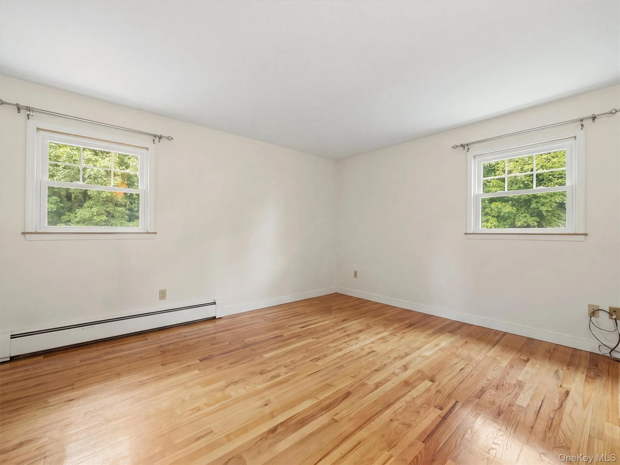 Hardwood flooring, two large windows, baseboard heating, and crisp white walls Hardwood flooring, two large windows, baseboard heating, and crisp white walls