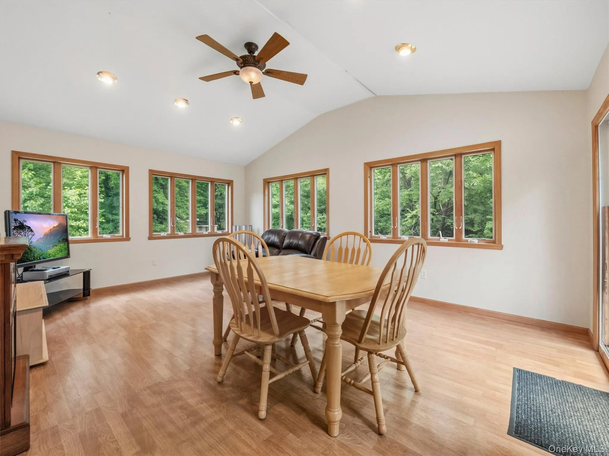 Vaulted ceilings, wood-finish flooring, numerous windows with wood trim, recessed lighting, and a ceiling fan Vaulted ceilings, wood-finish flooring, numerous windows with wood trim, recessed lighting, and a ceiling fan