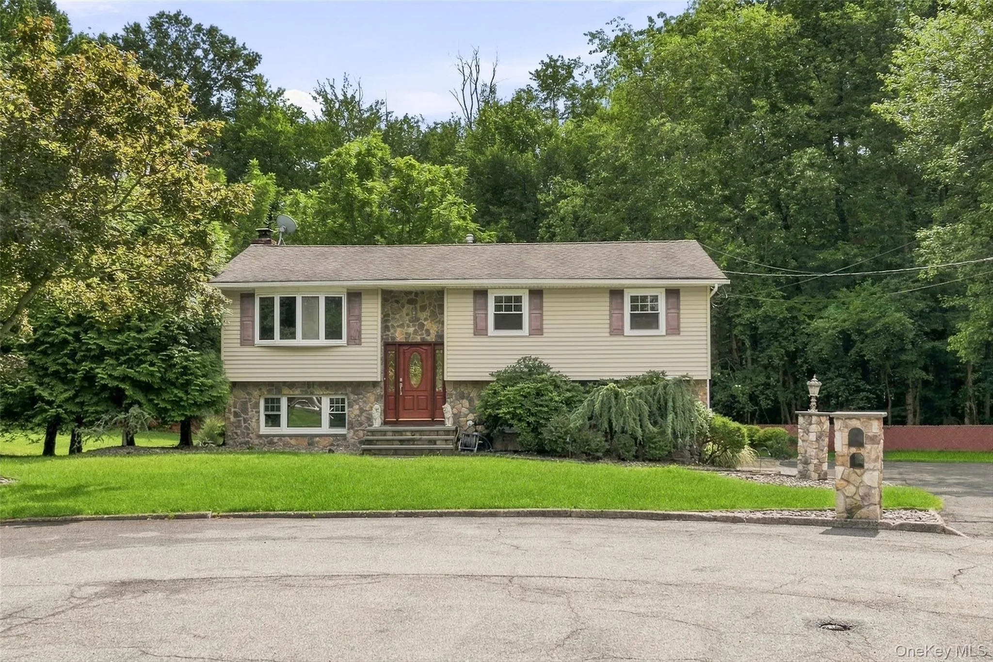 Residence in cul de sac featuring stone and siding exterior, bay window, and prominent red entry door Residence in cul de sac featuring stone and siding exterior, bay window, and prominent red entry door