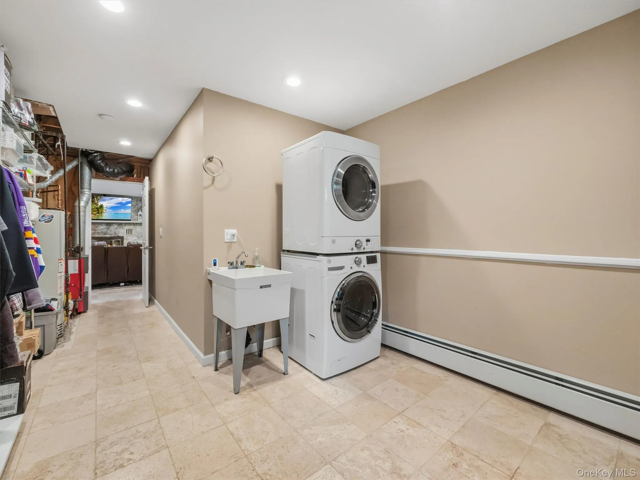 Floor-to-ceiling stacked laundry machines, utility sink, tile flooring, recessed ceiling lighting, and baseboard heating Floor-to-ceiling stacked laundry machines, utility sink, tile flooring, recessed ceiling lighting, and baseboard heating