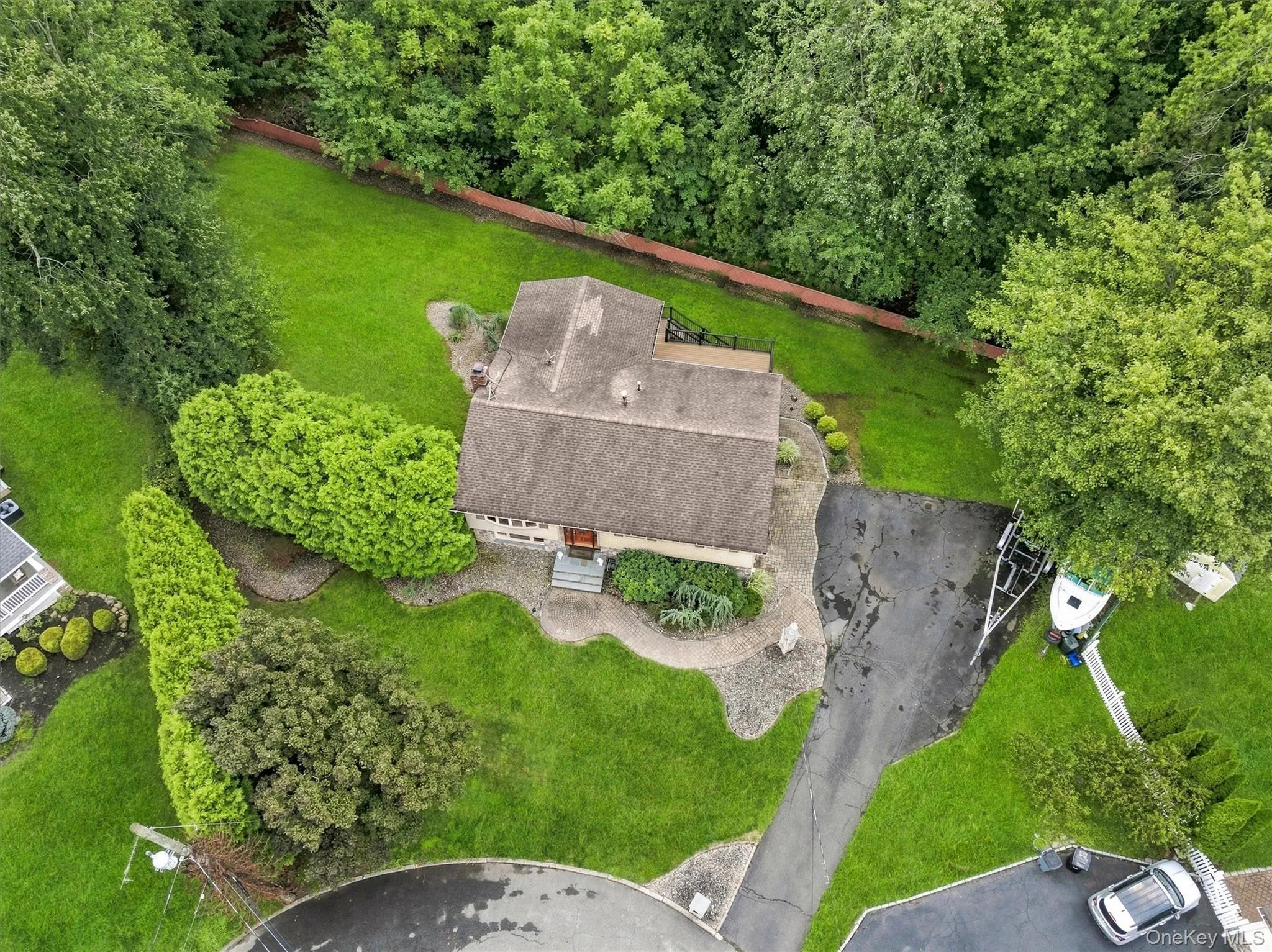 Expansive green lawn surrounds the residence, featuring a paved driveway and a stone pathway Expansive green lawn surrounds the residence, featuring a paved driveway and a stone pathway