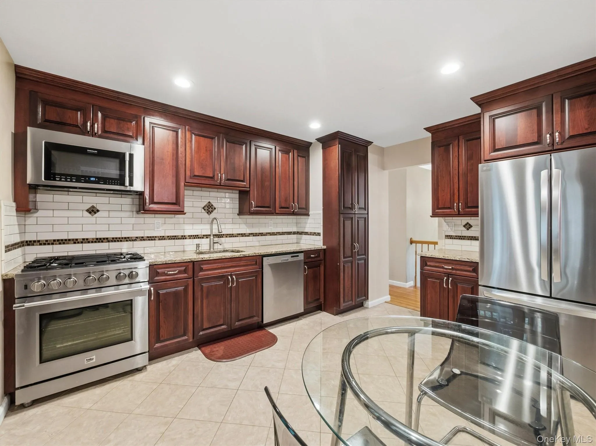 Kitchen featuring abundant cherry wood cabinetry, stainless steel appliances, granite countertops, subway tile backsplash, and recessed lighting Kitchen featuring abundant cherry wood cabinetry, stainless steel appliances, granite countertops, subway tile backsplash, and recessed lighting