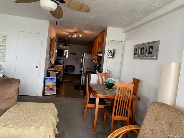Dining area featuring dark colored carpet, a textured ceiling, and ceiling fan Dining area featuring dark colored carpet, a textured ceiling, and ceiling fan
