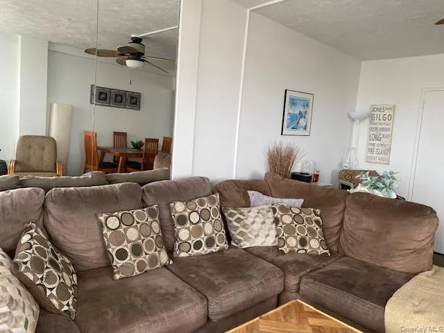 Living room featuring a textured ceiling and ceiling fan Living room featuring a textured ceiling and ceiling fan