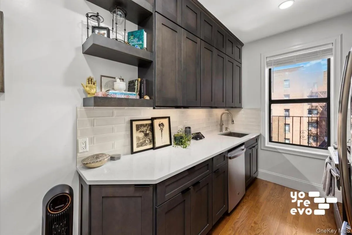 Dark wood-finish cabinetry, white countertop, subway tile backsplash, stainless steel sink with a gooseneck faucet, and wood-finish flooring Dark wood-finish cabinetry, white countertop, subway tile backsplash, stainless steel sink with a gooseneck faucet, and wood-finish flooring
