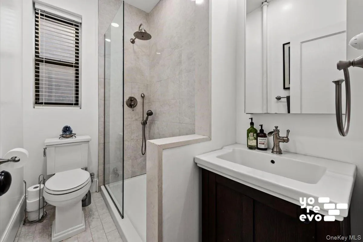 Walk-in shower with full glass enclosure and rainfall showerhead, integrated vanity sink with storage, and a built-in medicine cabinet Walk-in shower with full glass enclosure and rainfall showerhead, integrated vanity sink with storage, and a built-in medicine cabinet