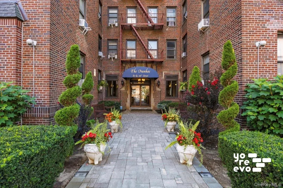Brick facade building with a paver walkway, manicured hedges, and ornamental plantings Brick facade building with a paver walkway, manicured hedges, and ornamental plantings