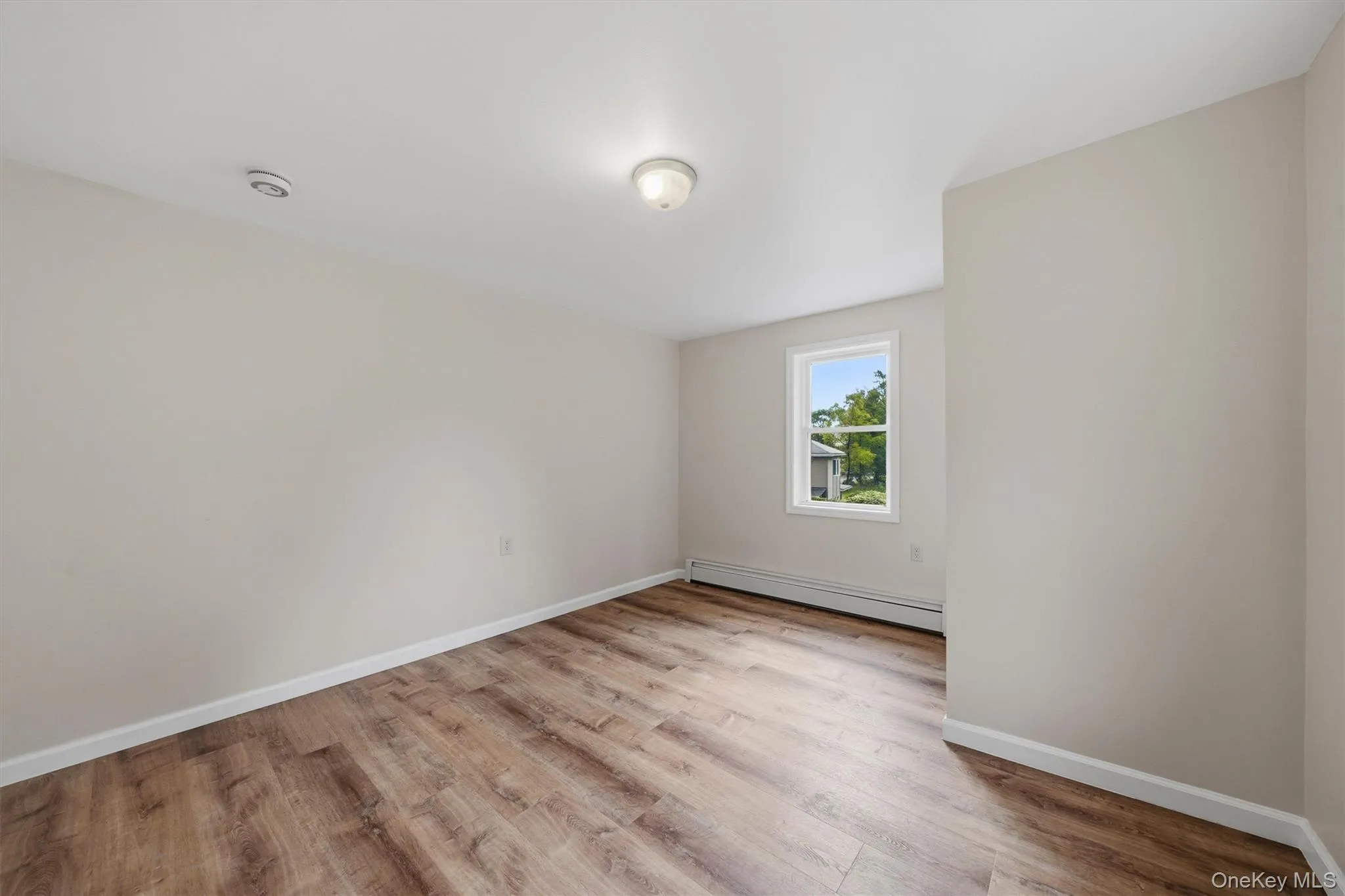 Wood-finish flooring, neutral wall tones, and a window with natural light Wood-finish flooring, neutral wall tones, and a window with natural light