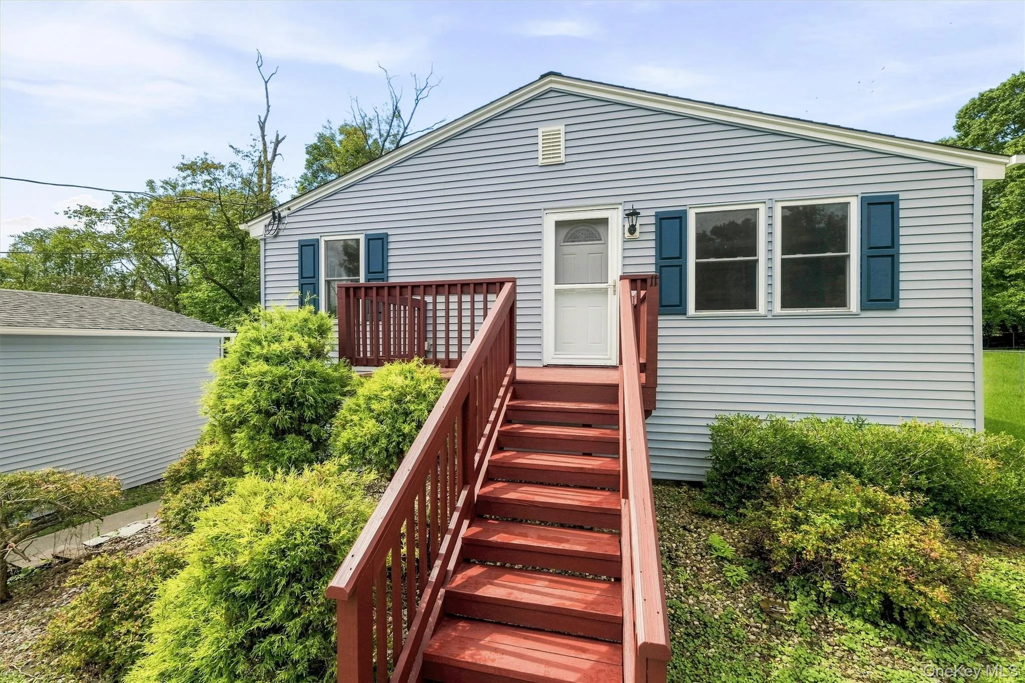 Light blue siding exterior with a red-stained wood deck and stairs Light blue siding exterior with a red-stained wood deck and stairs