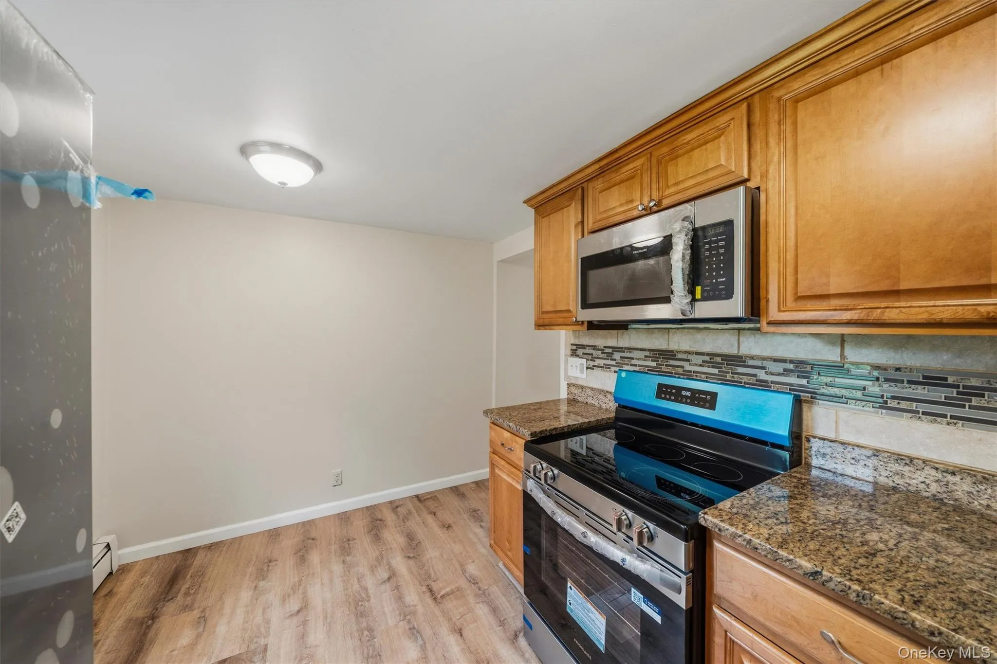 Wood-finish flooring, recessed lighting, wood cabinetry, stainless steel microwave, and granite countertops Wood-finish flooring, recessed lighting, wood cabinetry, stainless steel microwave, and granite countertops