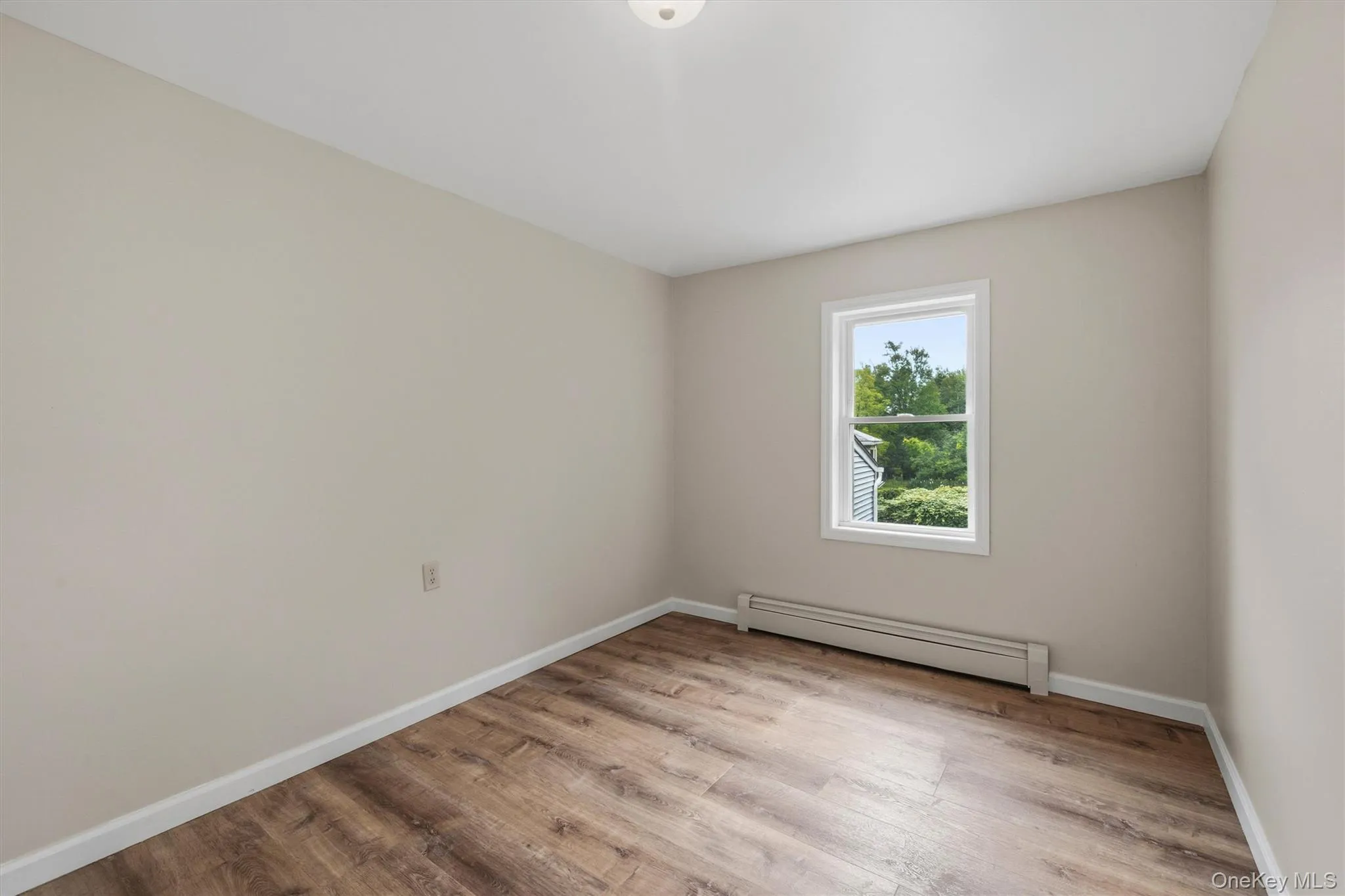 Wood-finish flooring, neutral wall paint, and a white-framed window Wood-finish flooring, neutral wall paint, and a white-framed window