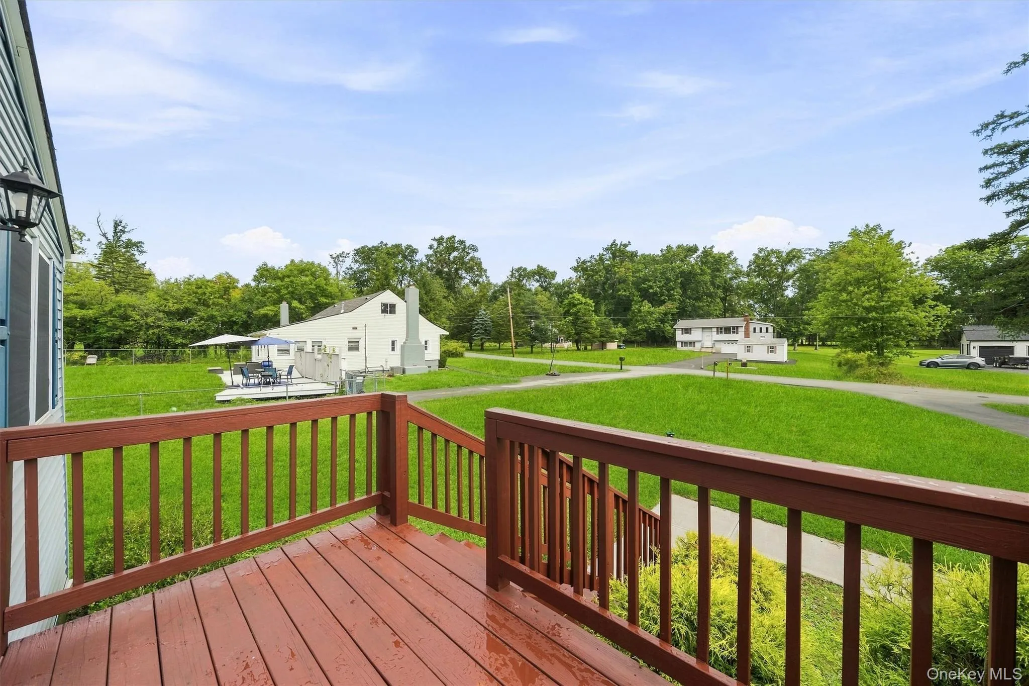 Expansive outdoor deck with red-toned wood decking and matching railings, bordered by green foliage Expansive outdoor deck with red-toned wood decking and matching railings, bordered by green foliage