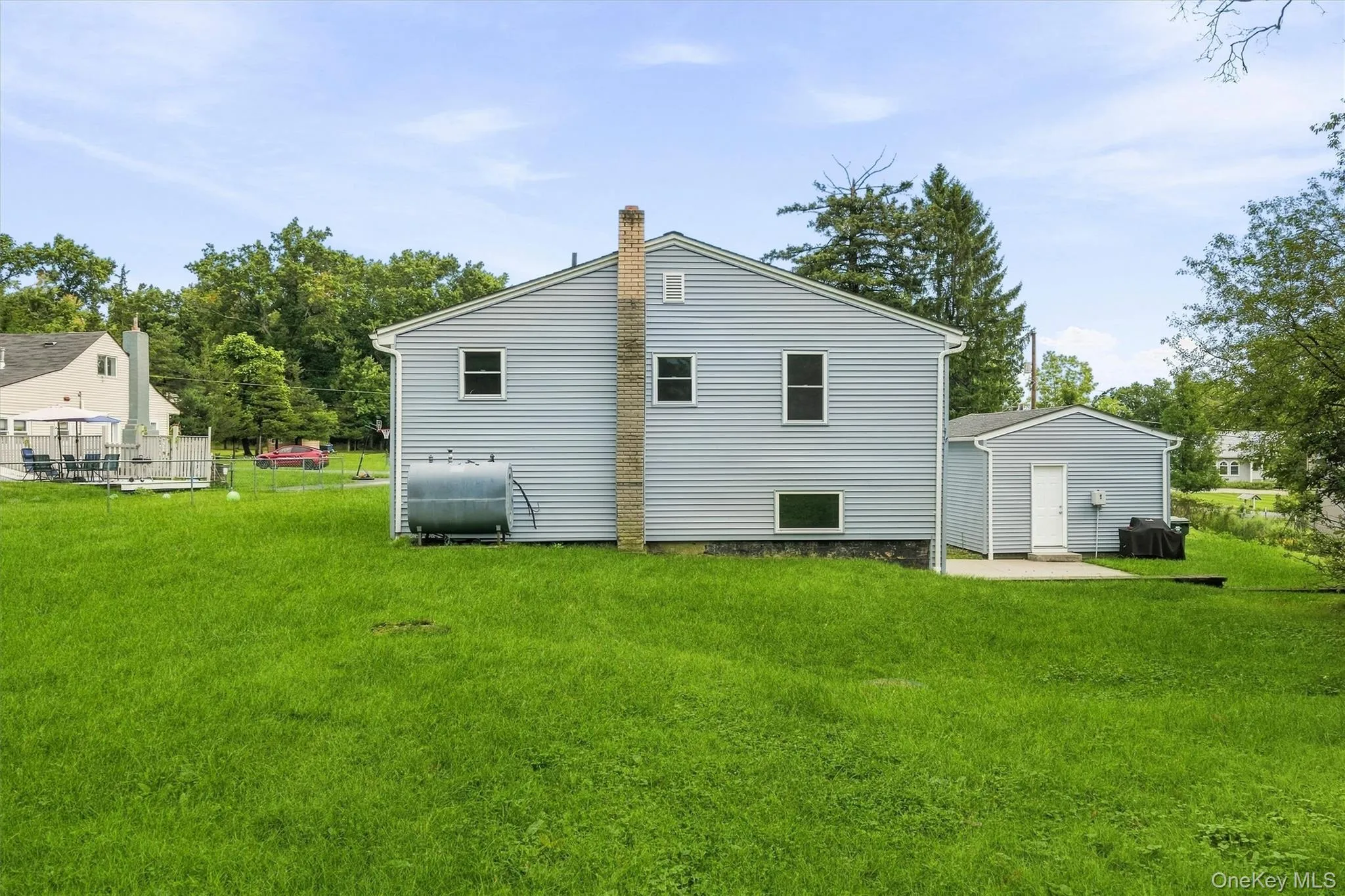 Expansive grassy yard with a detached garage and a concrete patio Expansive grassy yard with a detached garage and a concrete patio