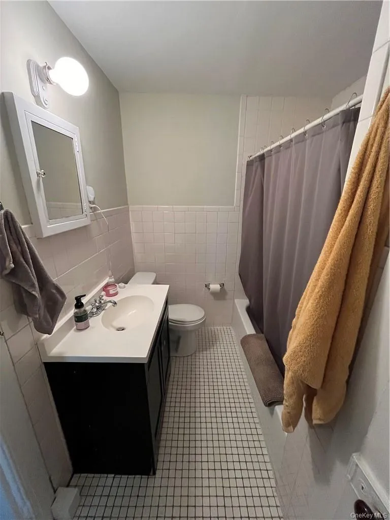 Full bathroom with tile walls, tile patterned flooring, decorative backsplash, toilet, and vanity Full bathroom with tile walls, tile patterned flooring, decorative backsplash, toilet, and vanity