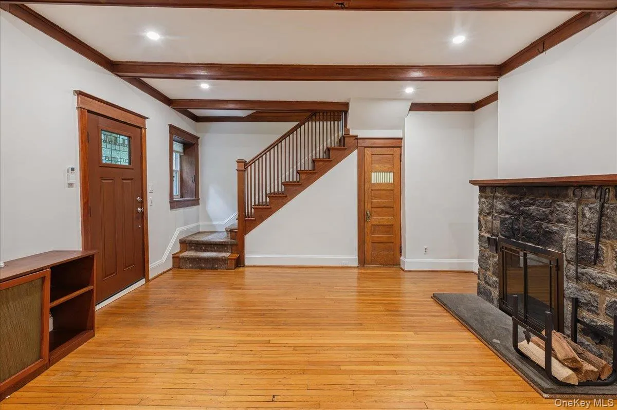 Lower level entrance to living room with wood burning fireplace and original oak stairway to main floor Lower level entrance to living room with wood burning fireplace and original oak stairway to main floor