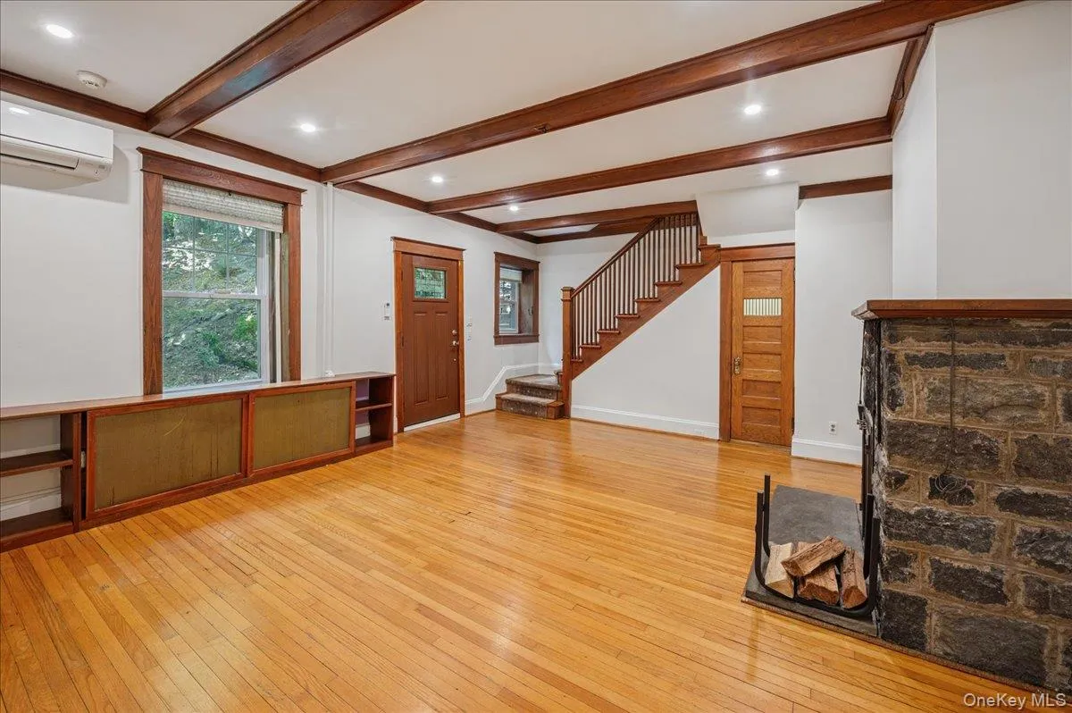Lower level view from the dining room into living room with original oak stairway to main floor Lower level view from the dining room into living room with original oak stairway to main floor