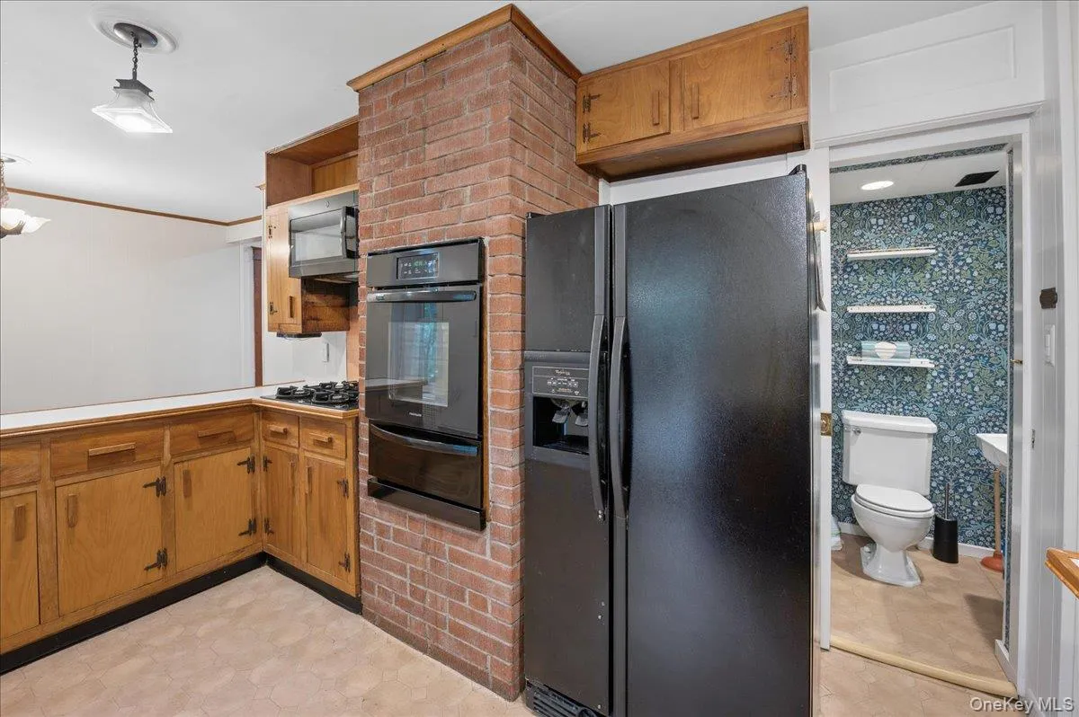 Lower level kitchen view with built in oven, microwave, gas cooktop, refrigerator and entrance to powder room Lower level kitchen view with built in oven, microwave, gas cooktop, refrigerator and entrance to powder room
