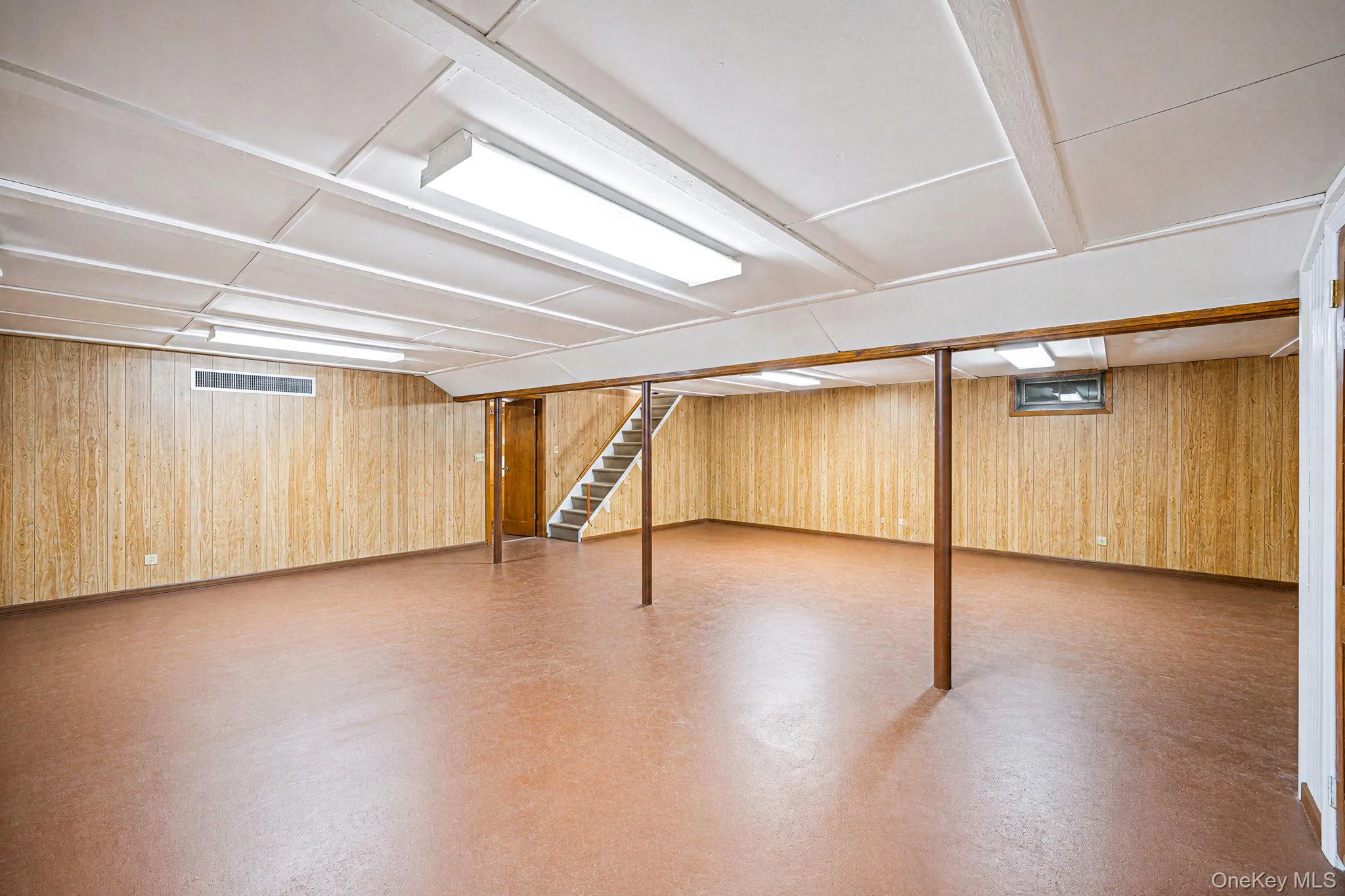 Expansive open space with wood-finish paneling and an acoustic tile ceiling Expansive open space with wood-finish paneling and an acoustic tile ceiling