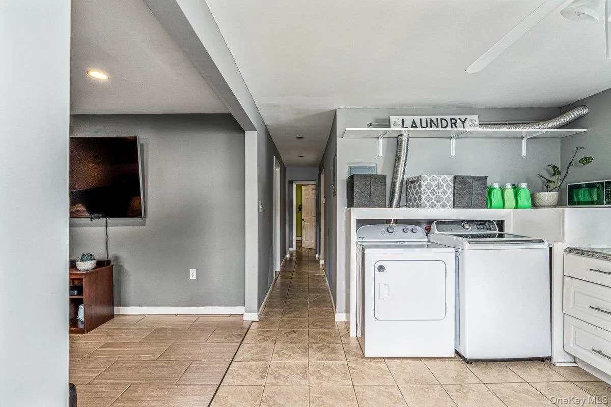 Laundry area featuring white appliances, upper shelving, and a built-in counter Laundry area featuring white appliances, upper shelving, and a built-in counter