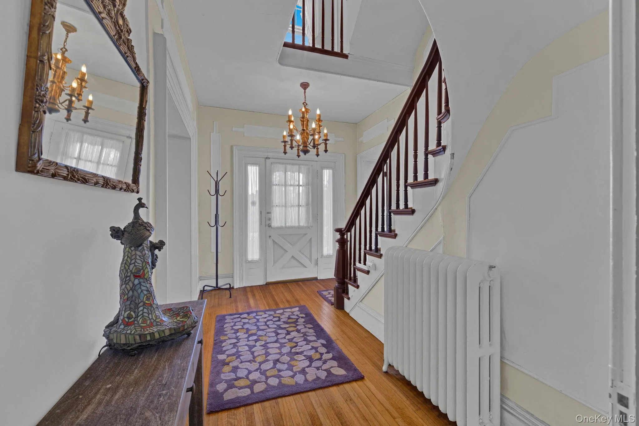 Entryway featuring radiator heating unit, hardwood / wood-style floors, and a chandelier Entryway featuring radiator heating unit, hardwood / wood-style floors, and a chandelier