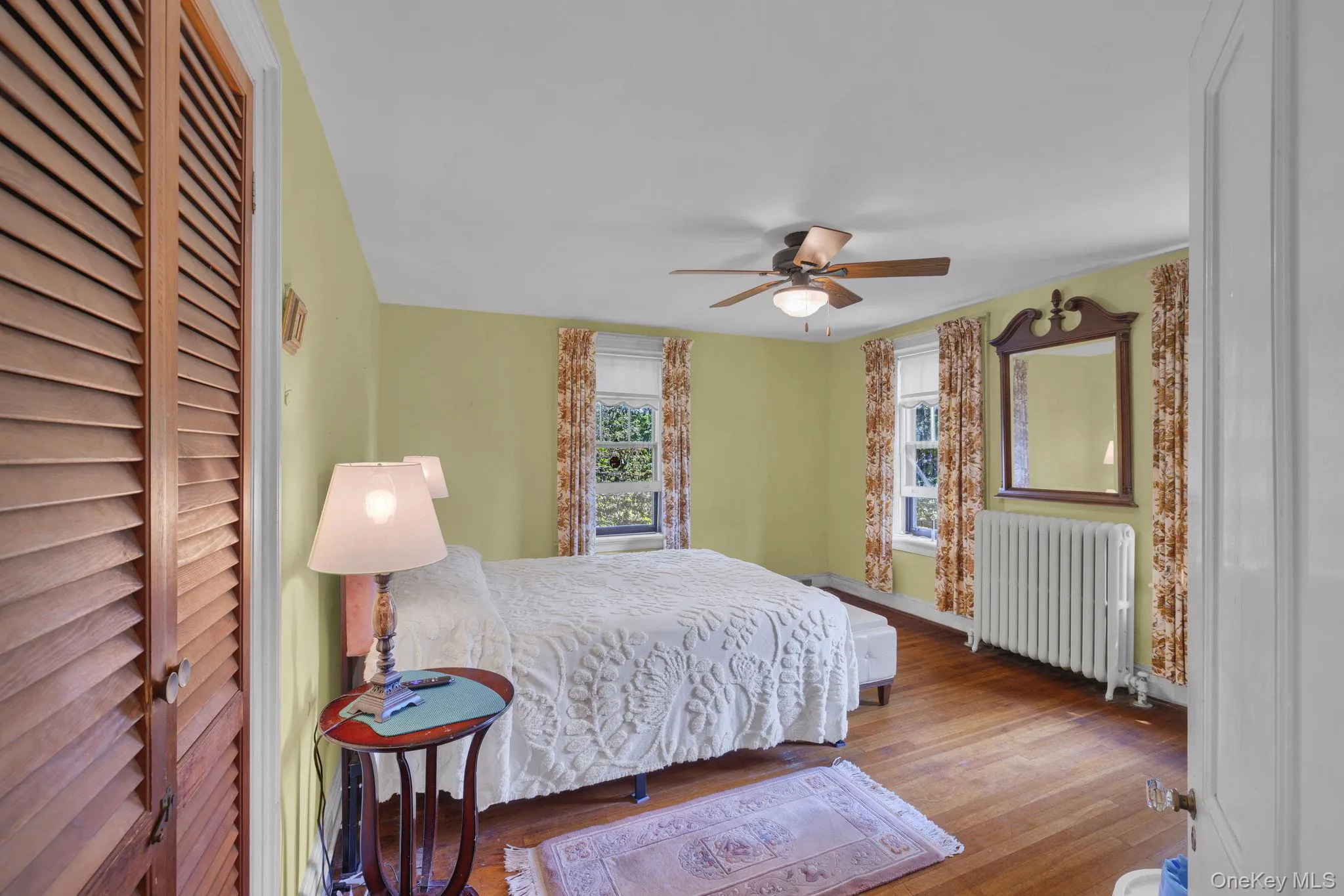 Bedroom featuring wood finished floors, radiator heating unit, and ceiling fan Bedroom featuring wood finished floors, radiator heating unit, and ceiling fan