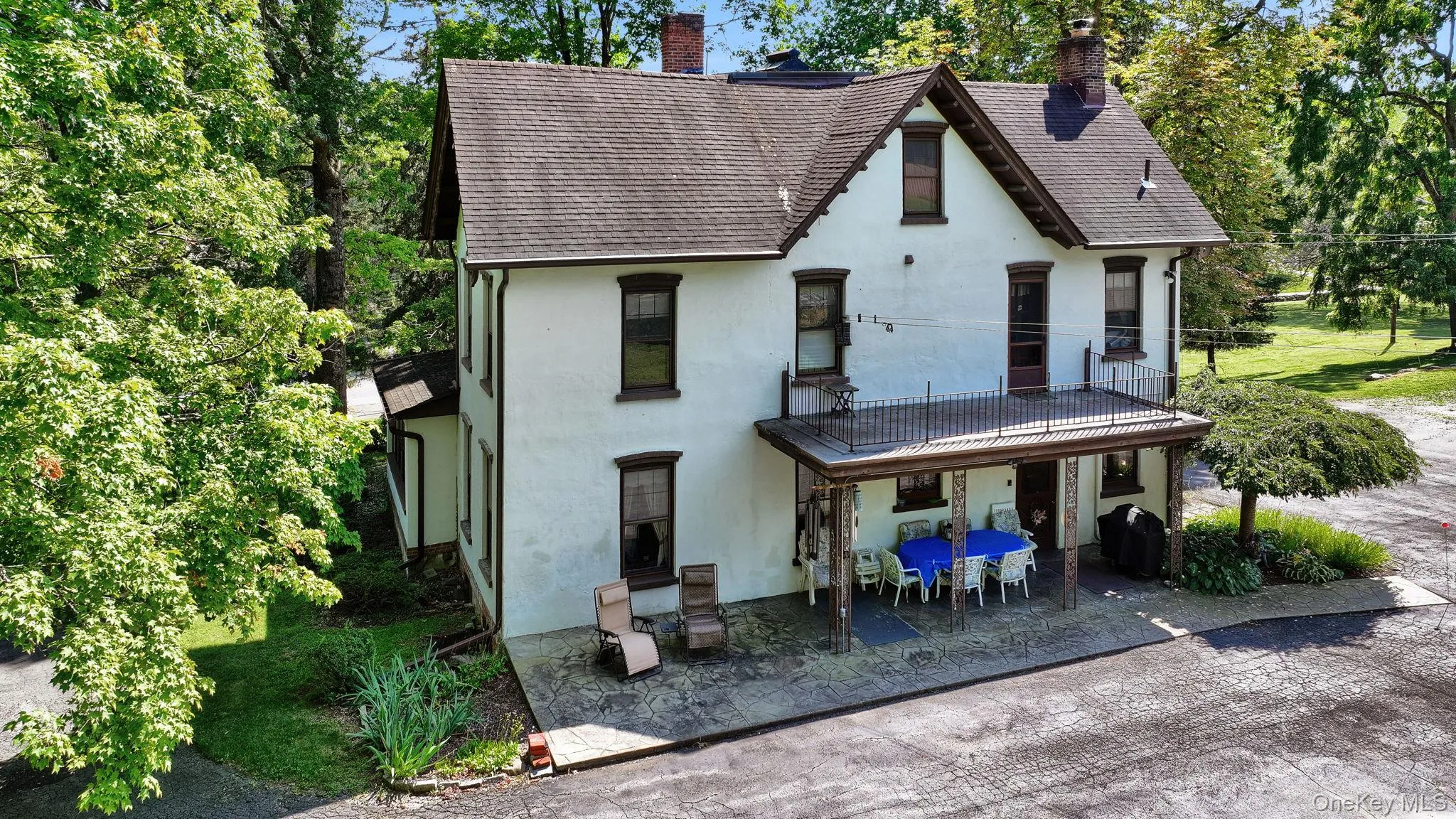 Back of property with a chimney, stucco siding, a patio, and roof with shingles Back of property with a chimney, stucco siding, a patio, and roof with shingles