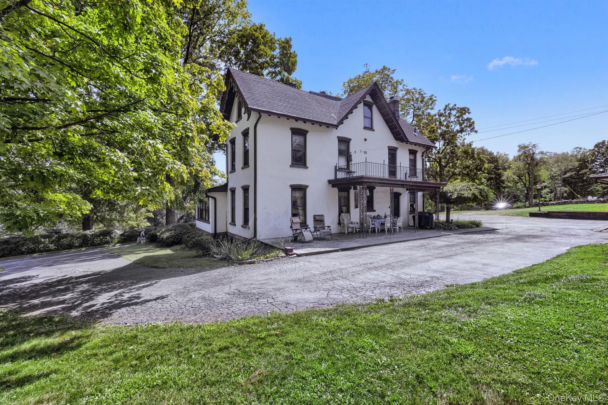 View of front of house with stucco siding, a balcony, a patio, a shingled roof, and a chimney View of front of house with stucco siding, a balcony, a patio, a shingled roof, and a chimney
