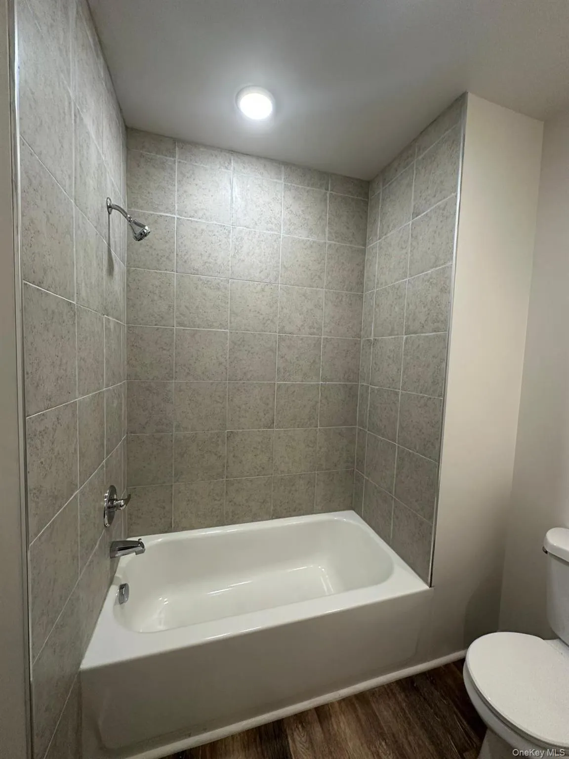 White bathtub with chrome fixtures and light-colored tile surround White bathtub with chrome fixtures and light-colored tile surround