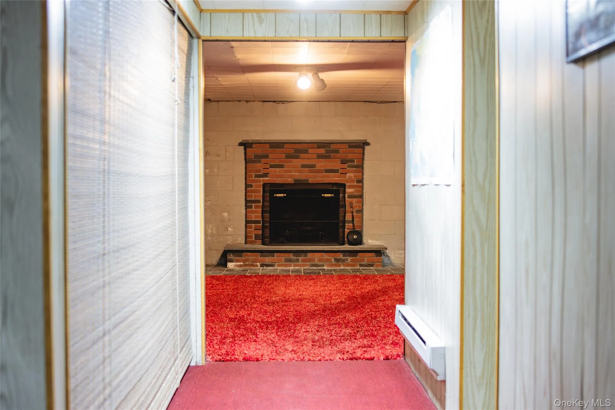 Hallway in basement leading to big open space with wood burning fireplace Hallway in basement leading to big open space with wood burning fireplace